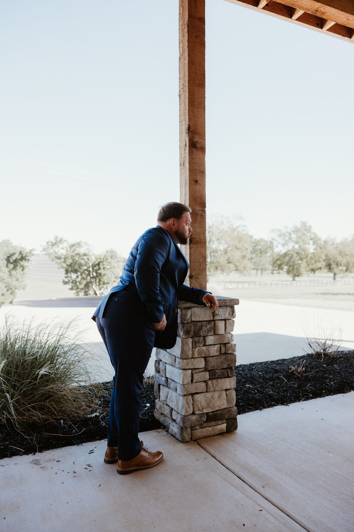 Sequence showing person in blue jacket near stone column on outdoor patio.