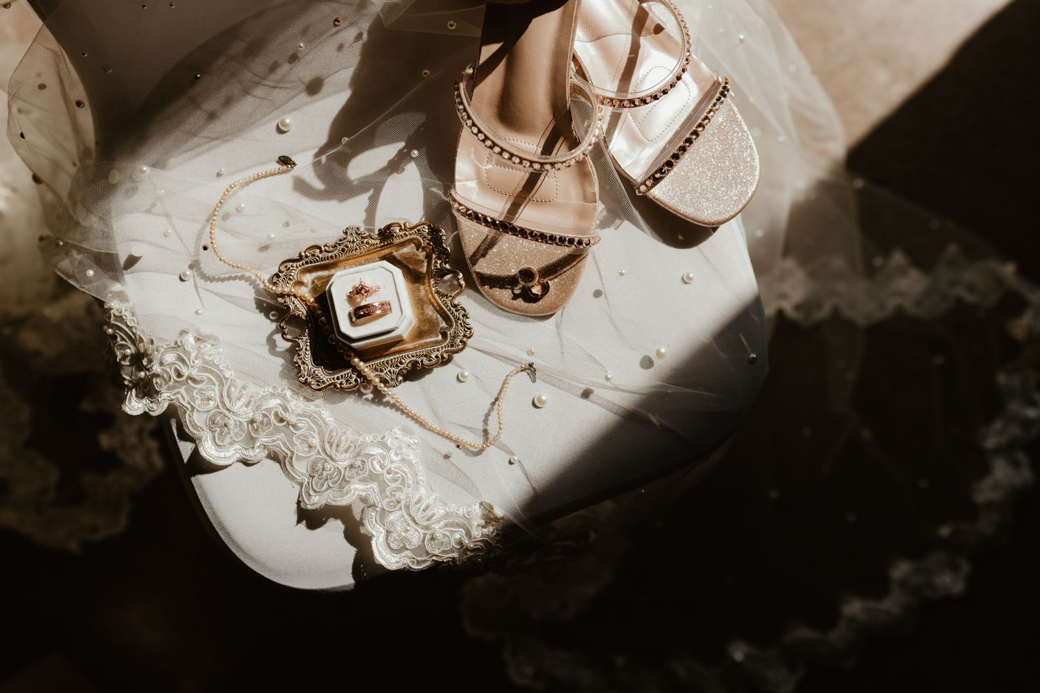 Elegant wedding scene arrangement featuring sparkling rose gold sandals and delicate lace details on a marble surface.