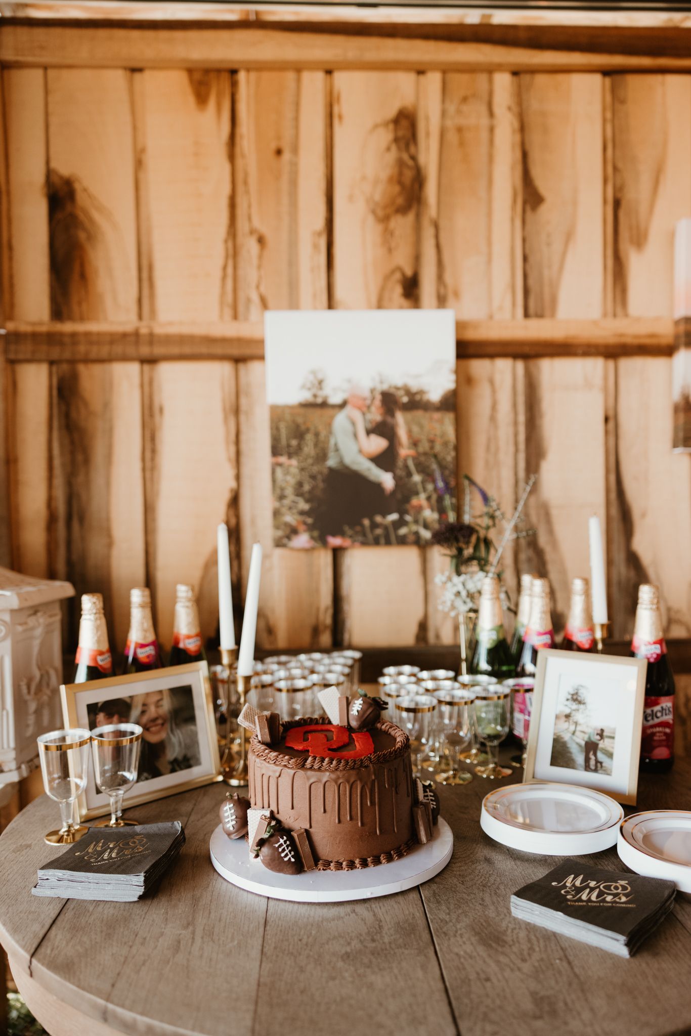 Several decorated chocolate cakes and desserts displayed on a rustic wooden table with candles and decorative elements.