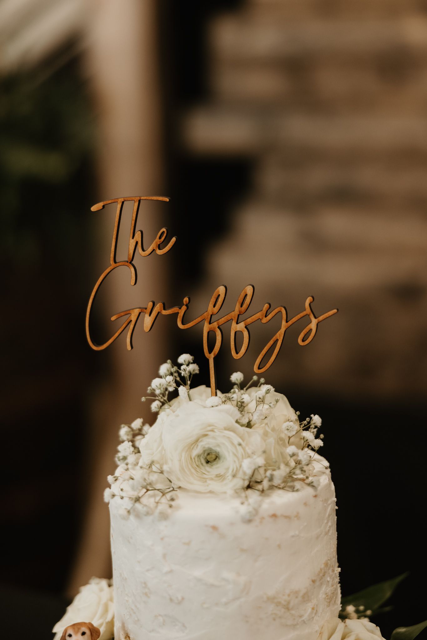 Elegant white wedding cake decorated with roses and baby's breath topped with cursive 