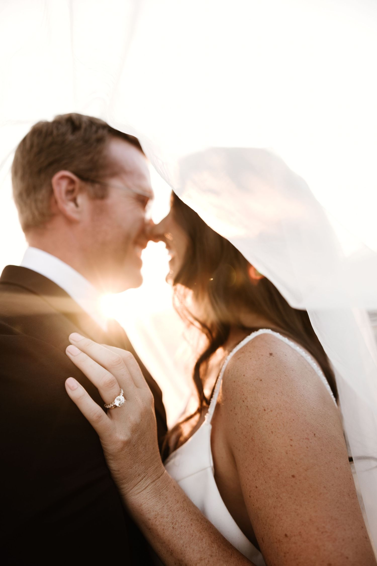 Romantic silhouette of couple sharing tender moment at sunset with sunlight creating a warm glow.