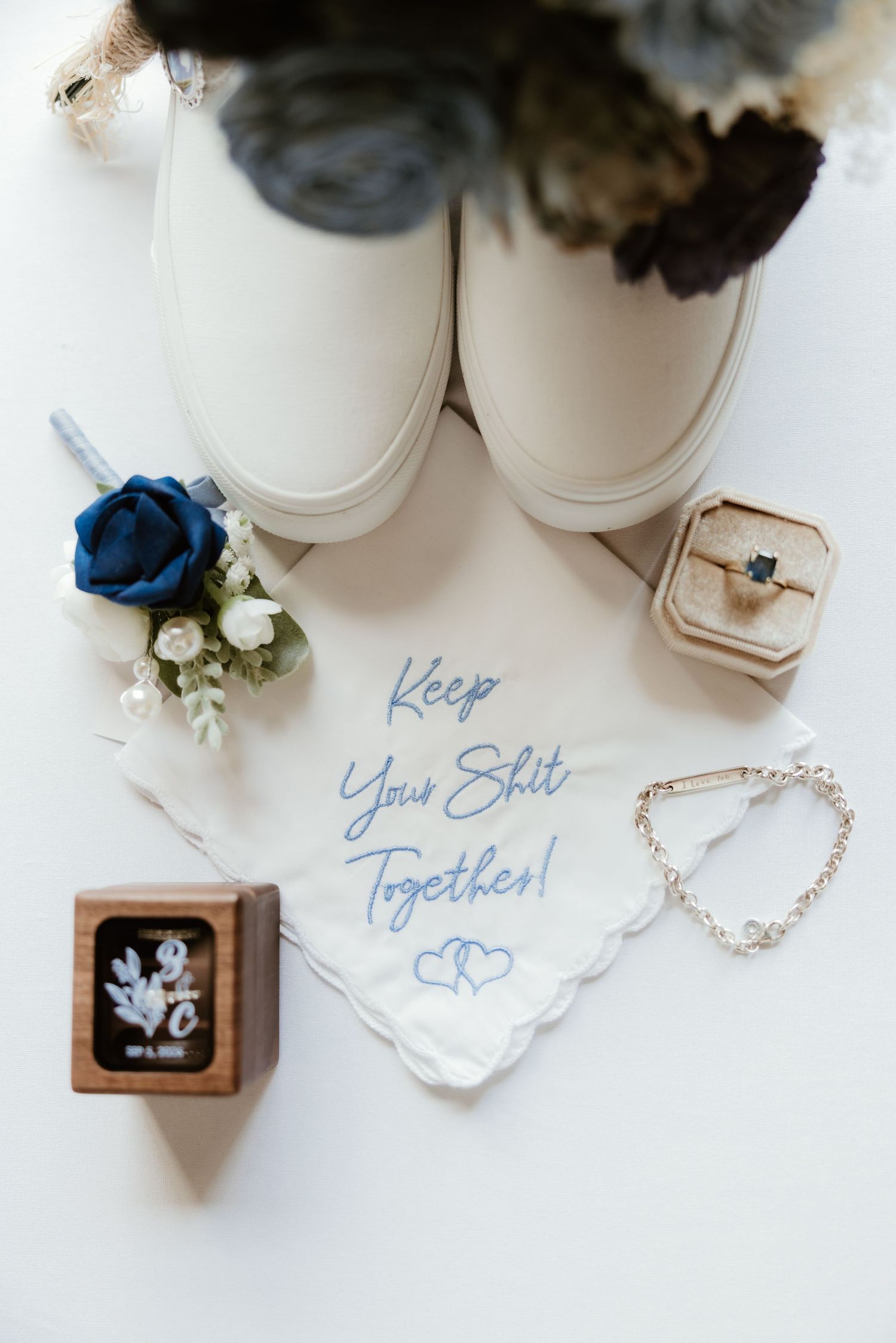 Wedding accessories and decor set in white, blue and beige including shoes, rings, flowers, and calligraphy notes.