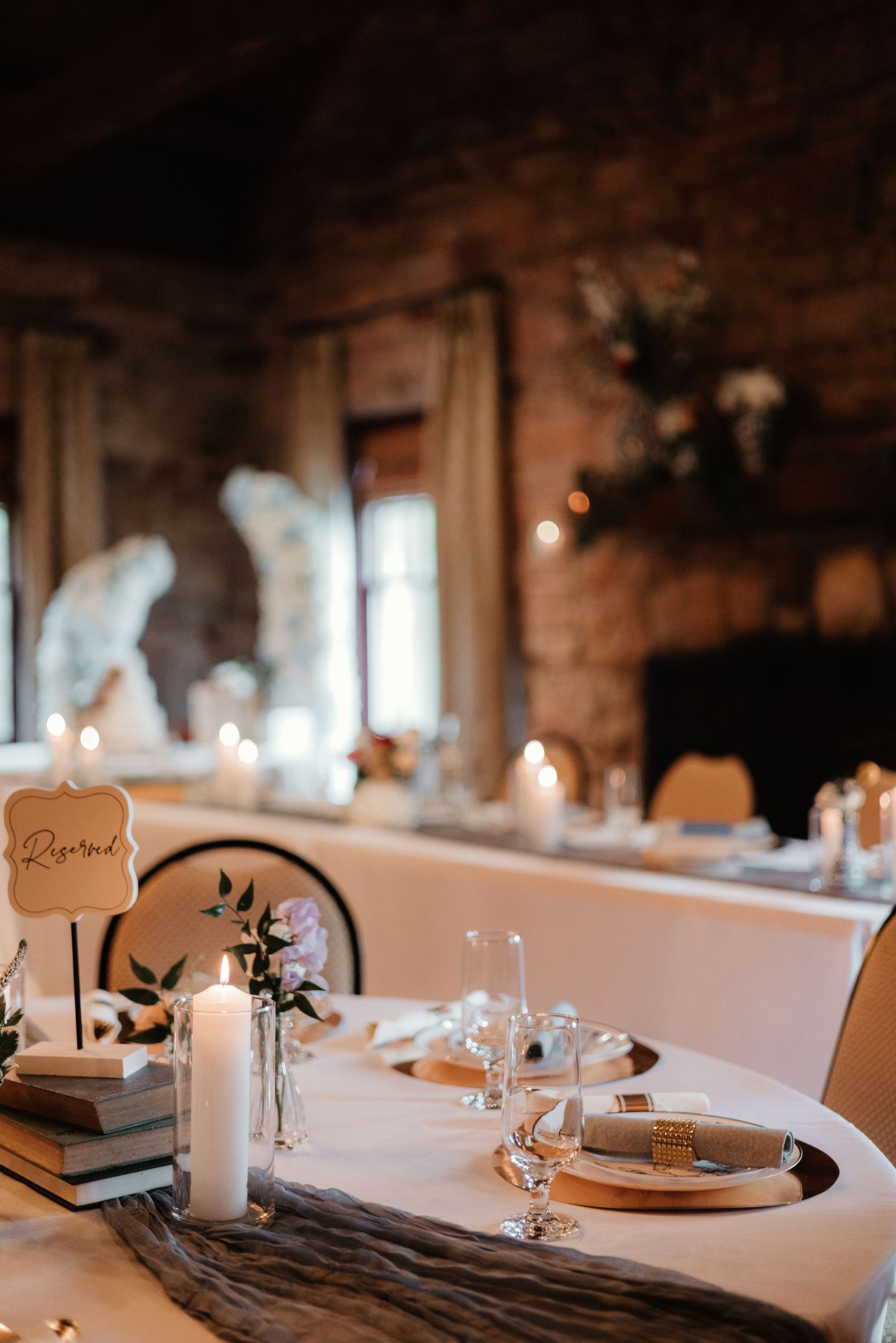 Romantic wedding table setup with candles and place settings in a rustic stone venue.