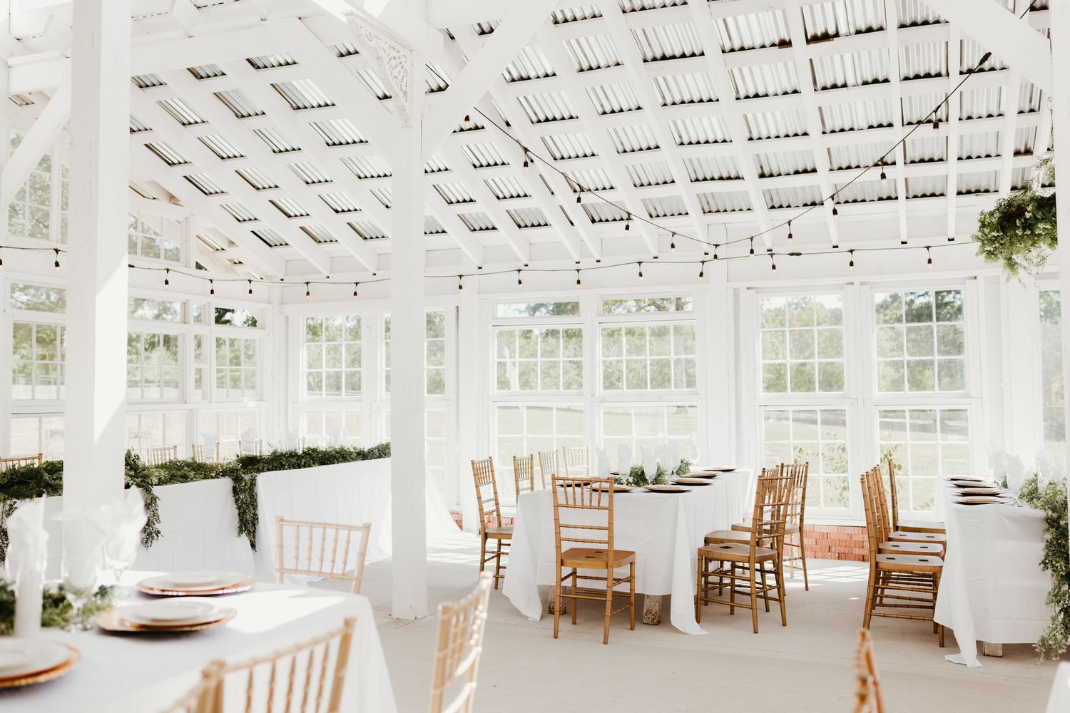 White lattice ceiling and windows create an elegant indoor-outdoor atmosphere in this bright reception venue space.
