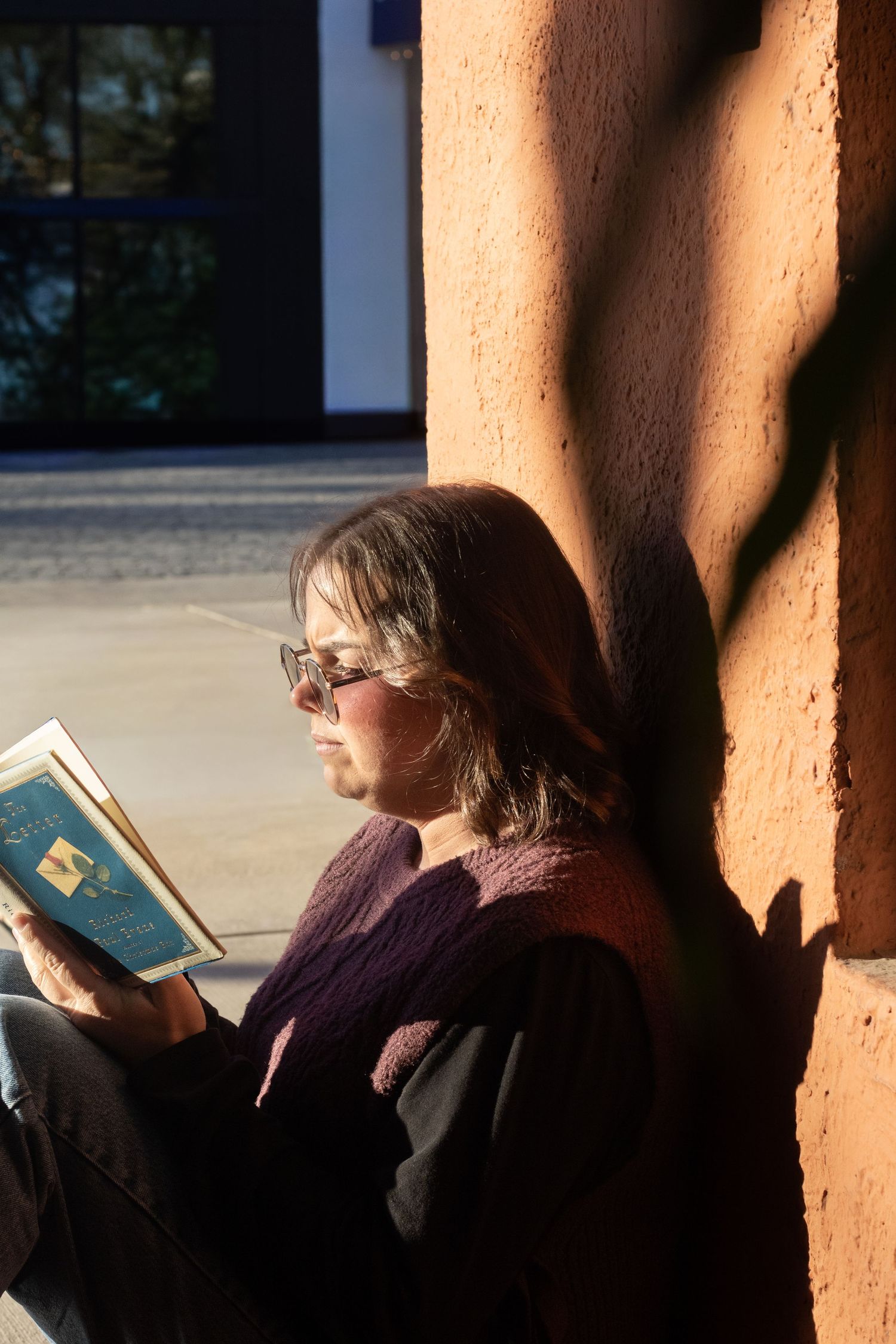 Moody warm lighting that is abstract. She's sitting outside reading a book the sunlight is hitting her to make her look highlighted.