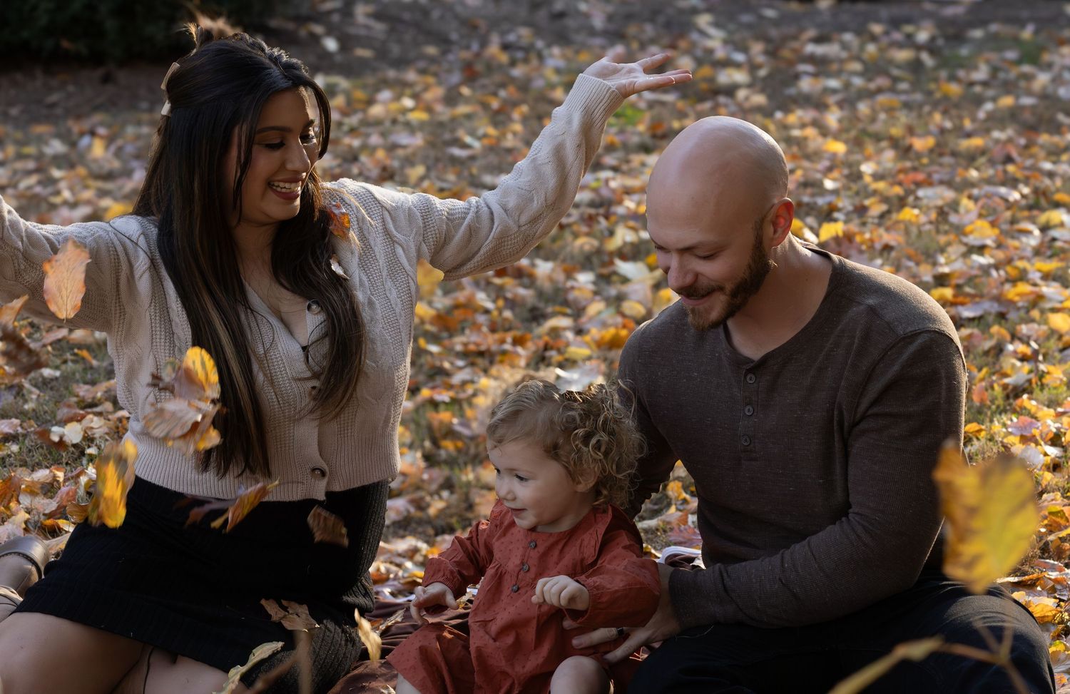 a family in throwing up leaves in the sky with the fall colors. the picture shows the leaves falling in the frame of the photo
