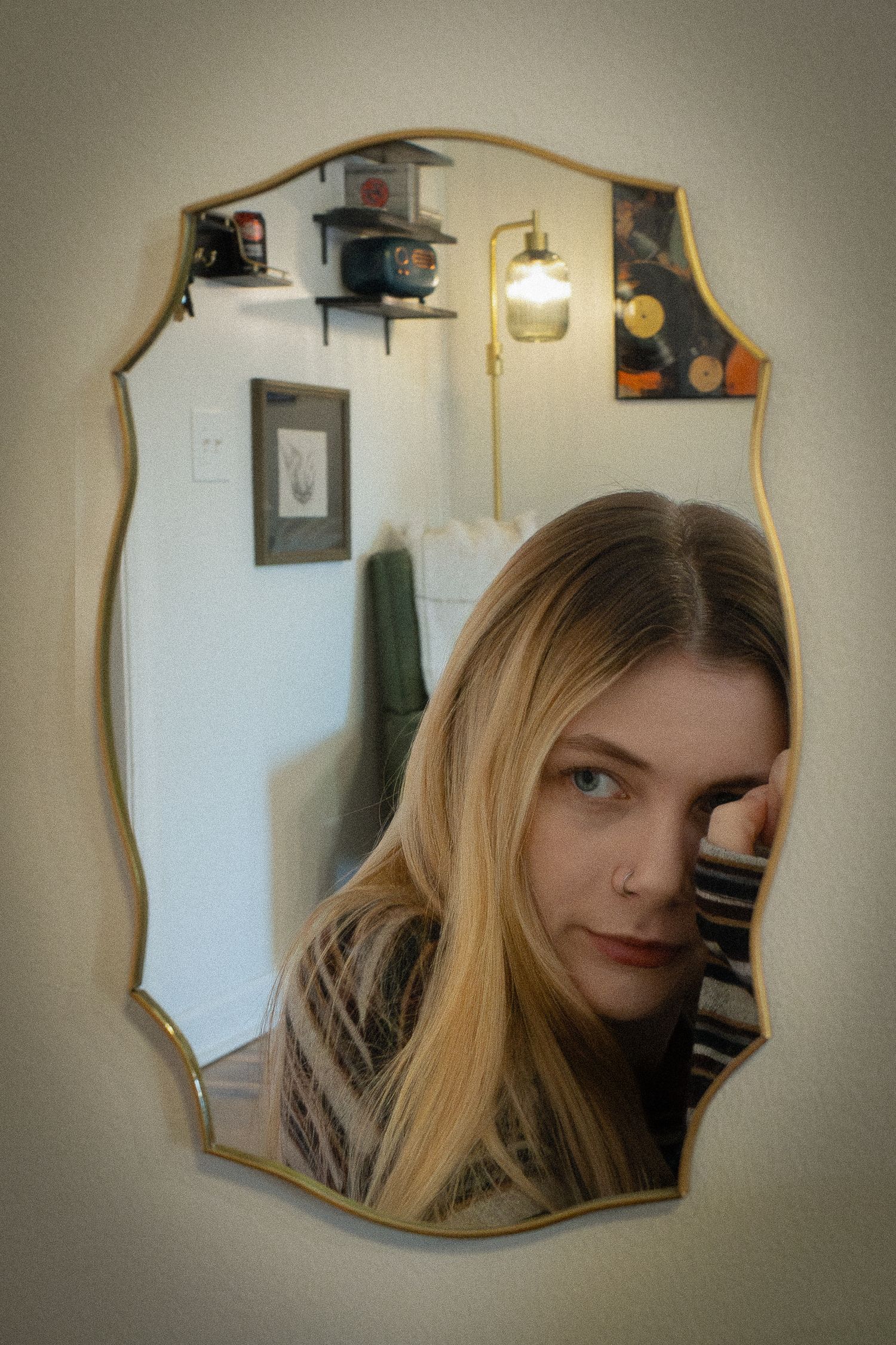 An artsy picture of a women looking in a mirror. Grain has been added to make the picture have more texture. It's a moody feeling picture.