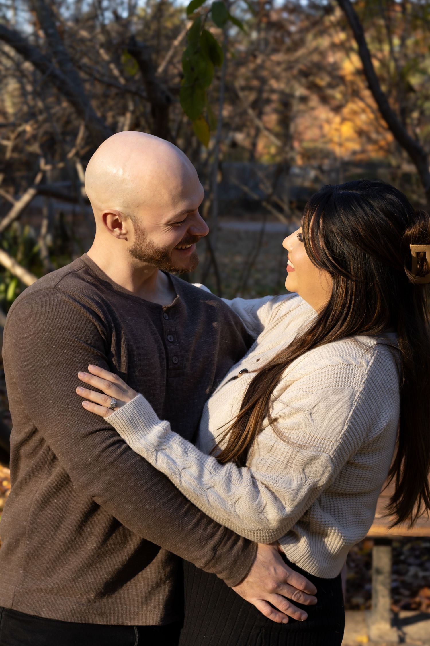 A couple's portrait of a husband and wife during fall. they're looking at each other with love. The lighting is warm and cozy
