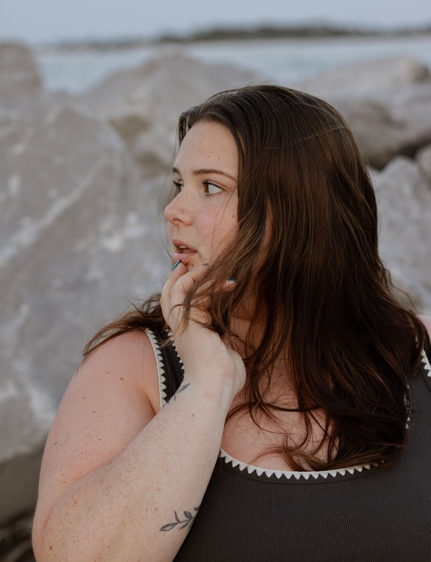 an up-close portrait at blue hour. the colors are suttle and cool. the background of rocks is picked to make her stand out.