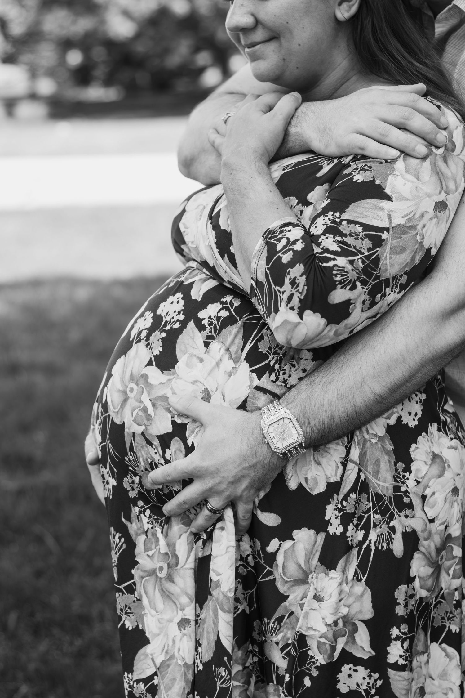 Black and white photo of couple embracing, man holding pregnant woman's baby bump tenderly.