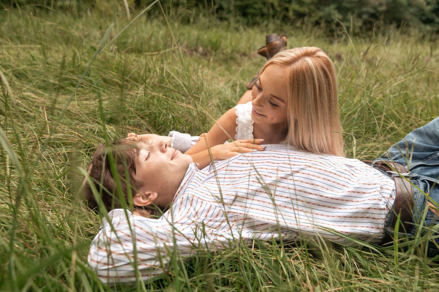 A woman and child lying in green grass, smiling and enjoying a playful moment together outdoors. Rome, GA