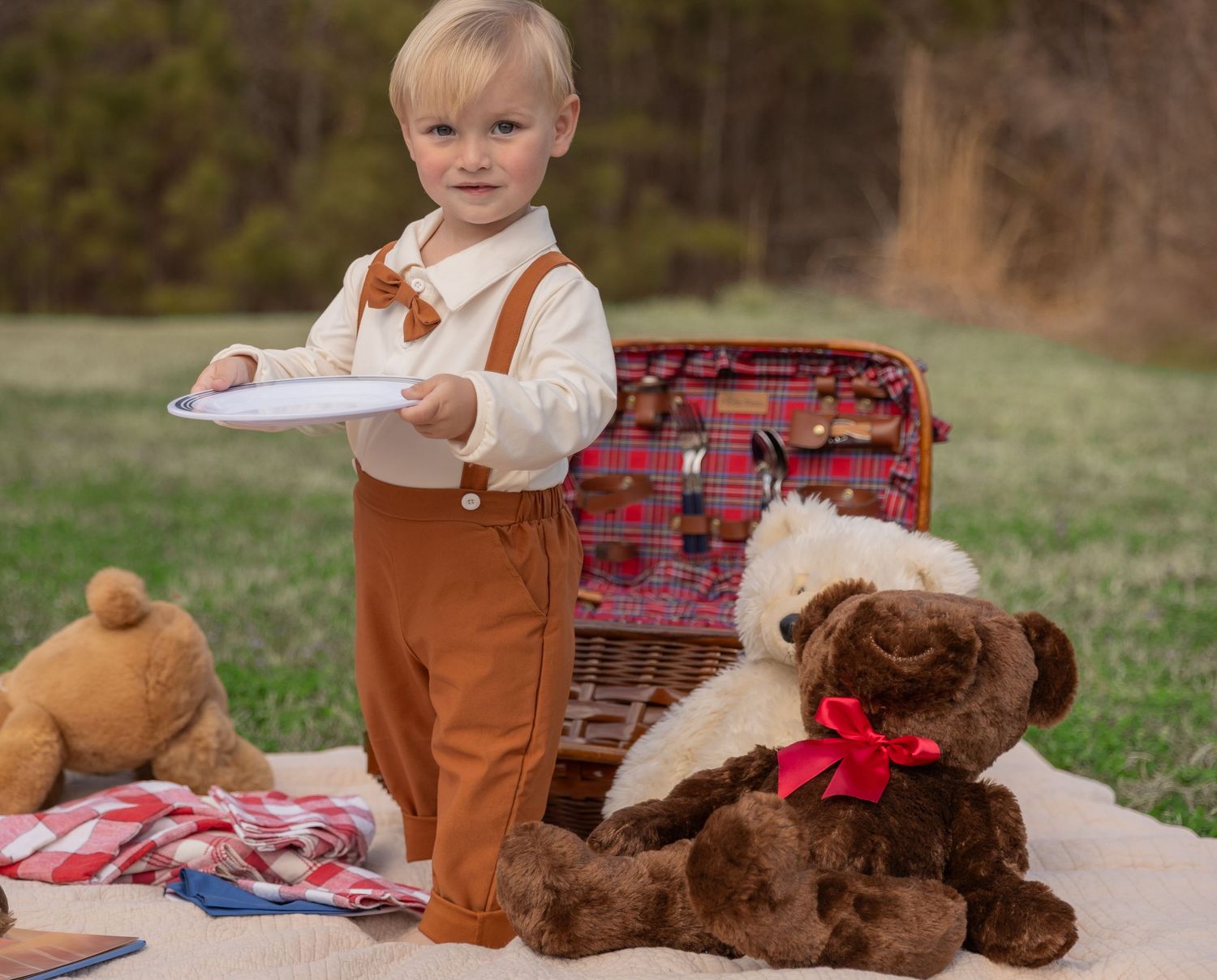 A child in brown stands with teddy bears and plaid blankets during an outdoor photo session.  Rome, GA Jessica M Cooper Photography LLC