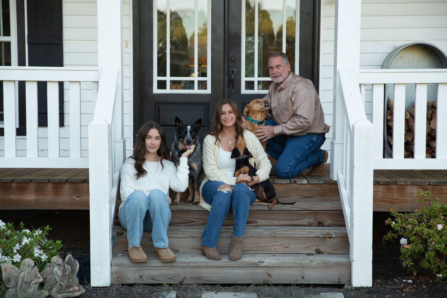 A family sits casually on white wooden porch steps of a traditional home with family pets- Rome GA Jessica M Cooper Photography LLC
