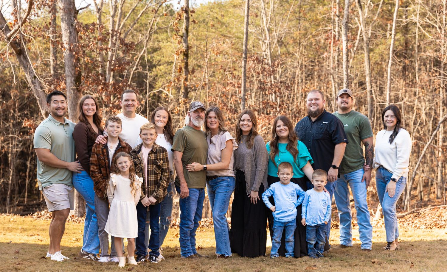 Large family group poses together outdoors in casual attire against autumn trees and foliageJessica M Cooper Photography LLC Rome GA