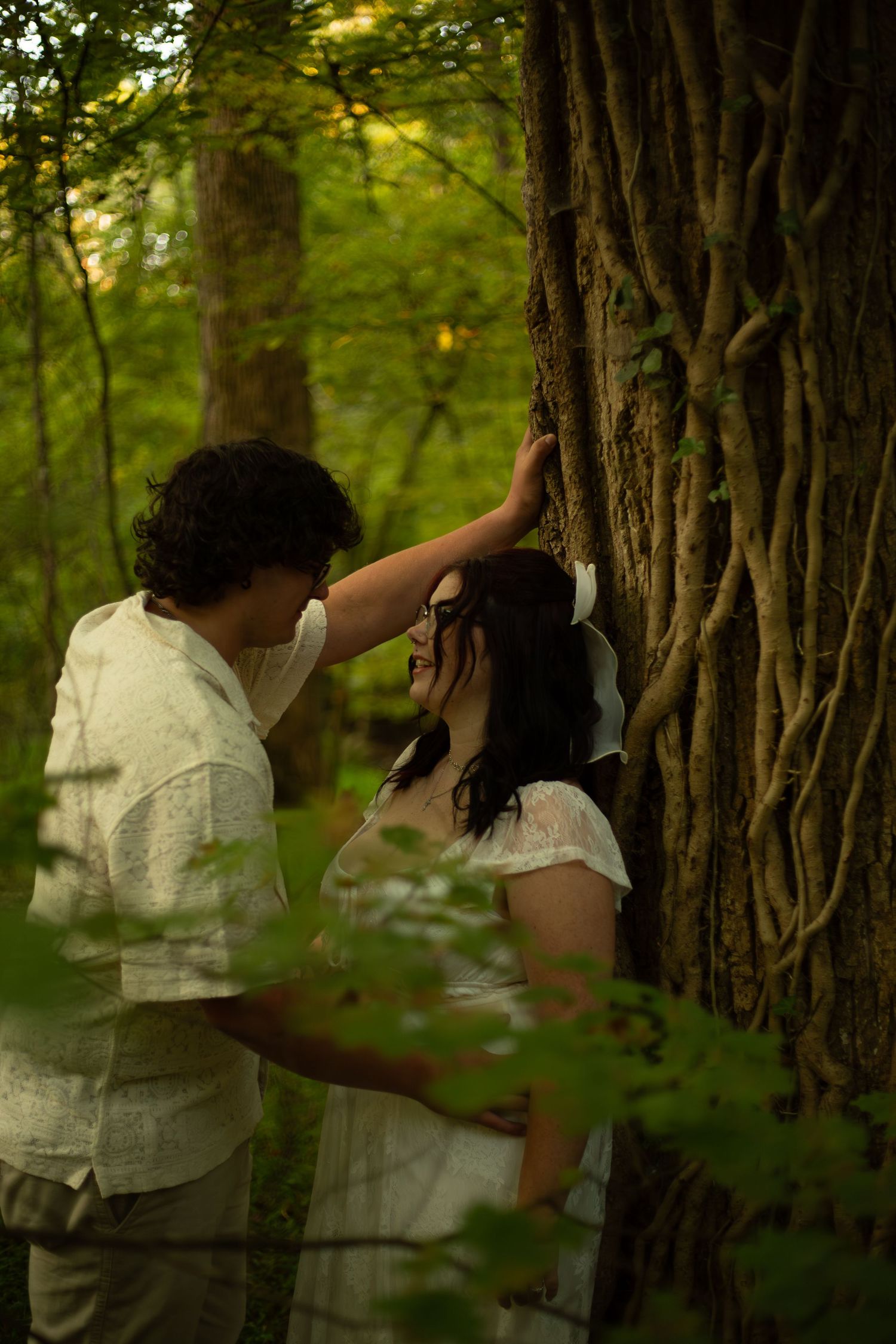 Couple in white clothing sharing intimate moment among trees in sunlit forest-Jessica M Cooper Photography LLC Rome GA