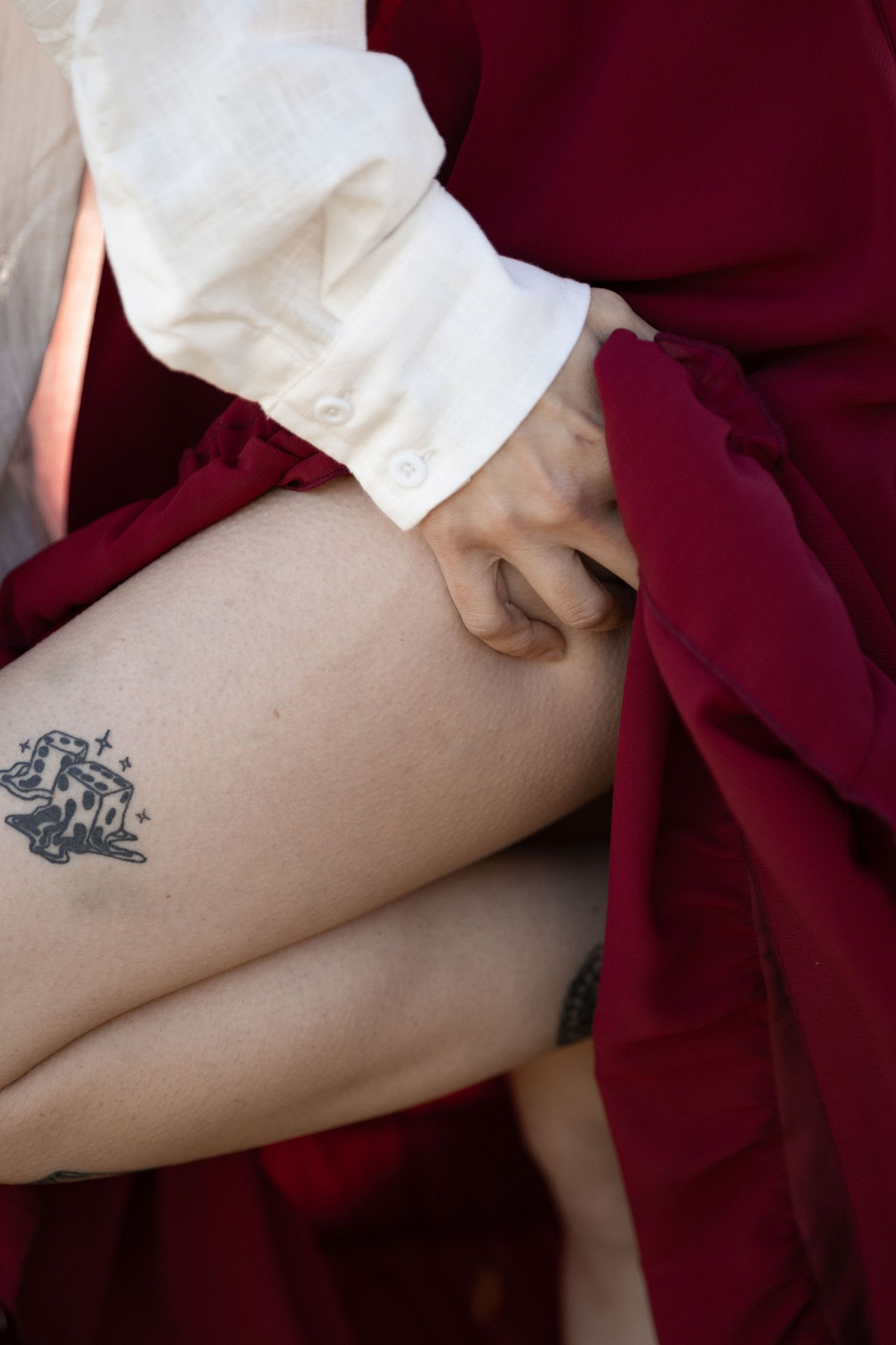 Close-up of a leg tattoo reading 'two' beside red fabric dress and white sleeve. Berry College Rome, GA