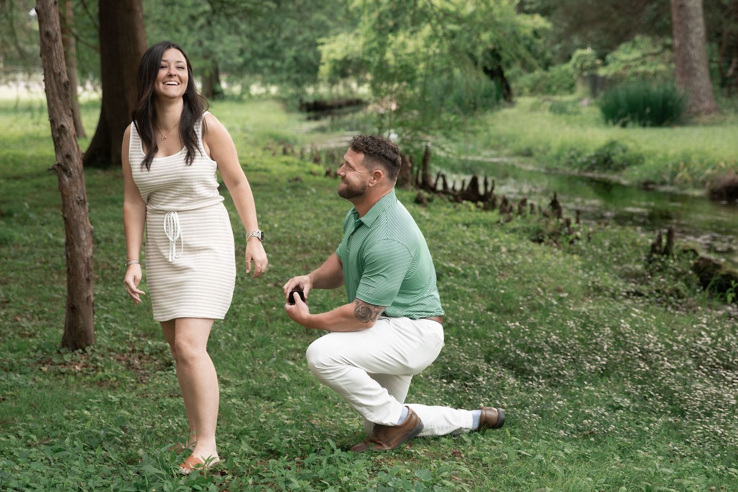 Man kneeling on one knee proposing to a woman in a lush green park setting. Cedartown, GA
