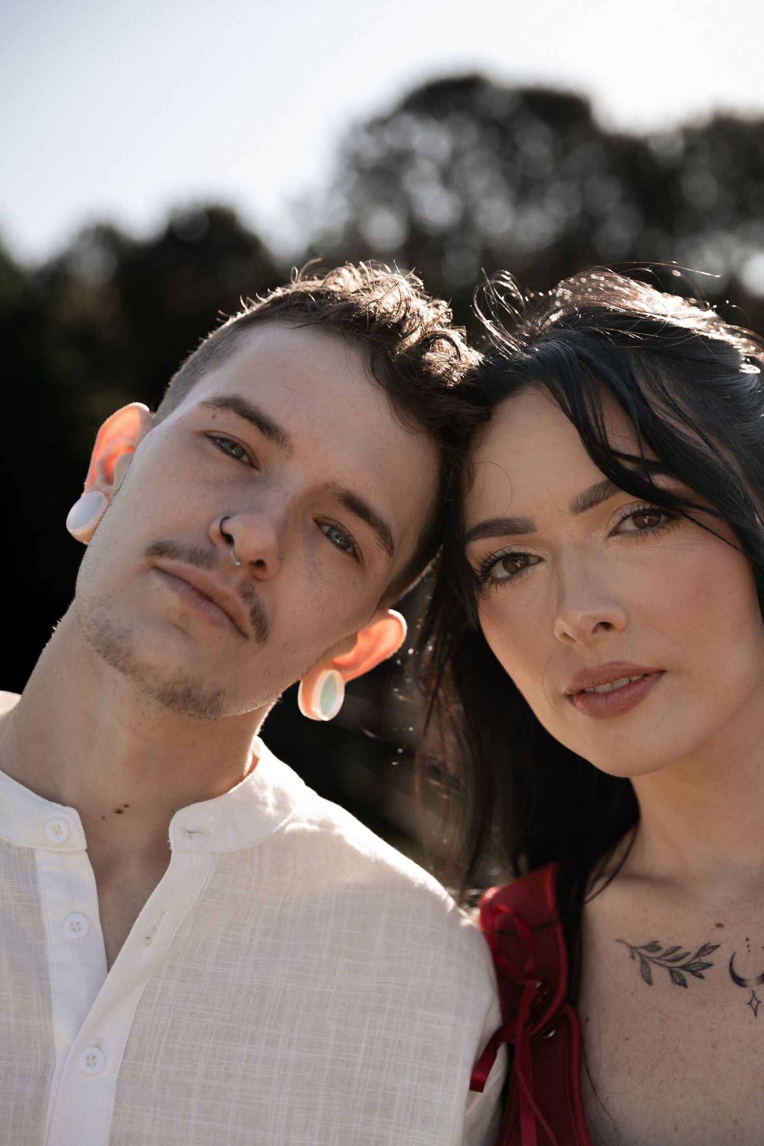 Young couple posing together outdoors, woman with chest tattoo leaning on mans shoulder in natural light. Berry College Rome, GA