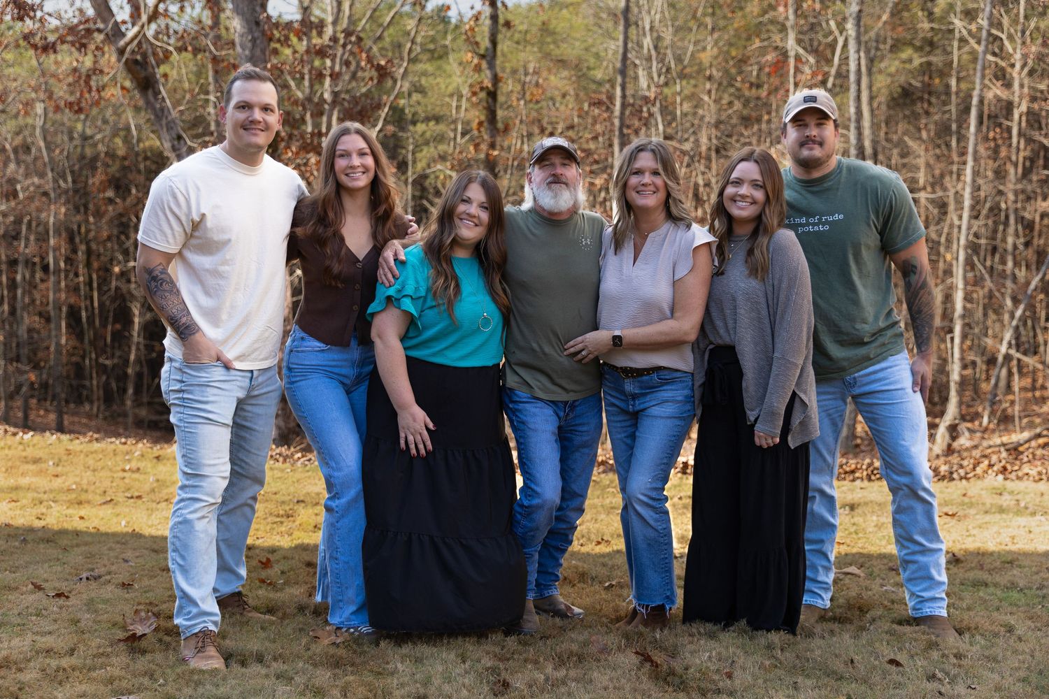 A large family wearing casual clothing pose together outdoors on a sunny day with trees in the background- Northwest Georgia