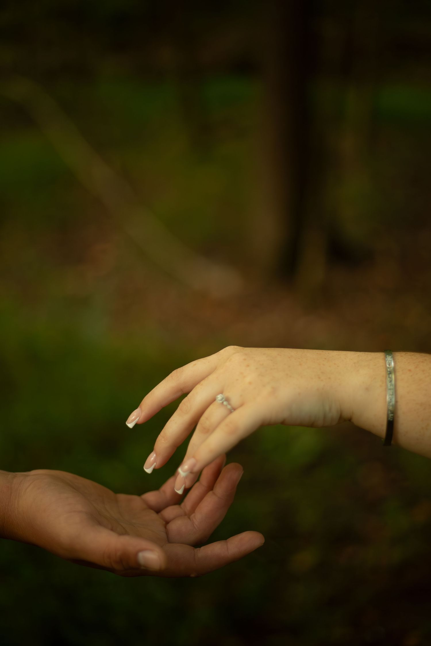 Close-up sequence of two hands reaching out and touching in a romantic gesture against a dark background-Jessica M Cooper Photography LLC