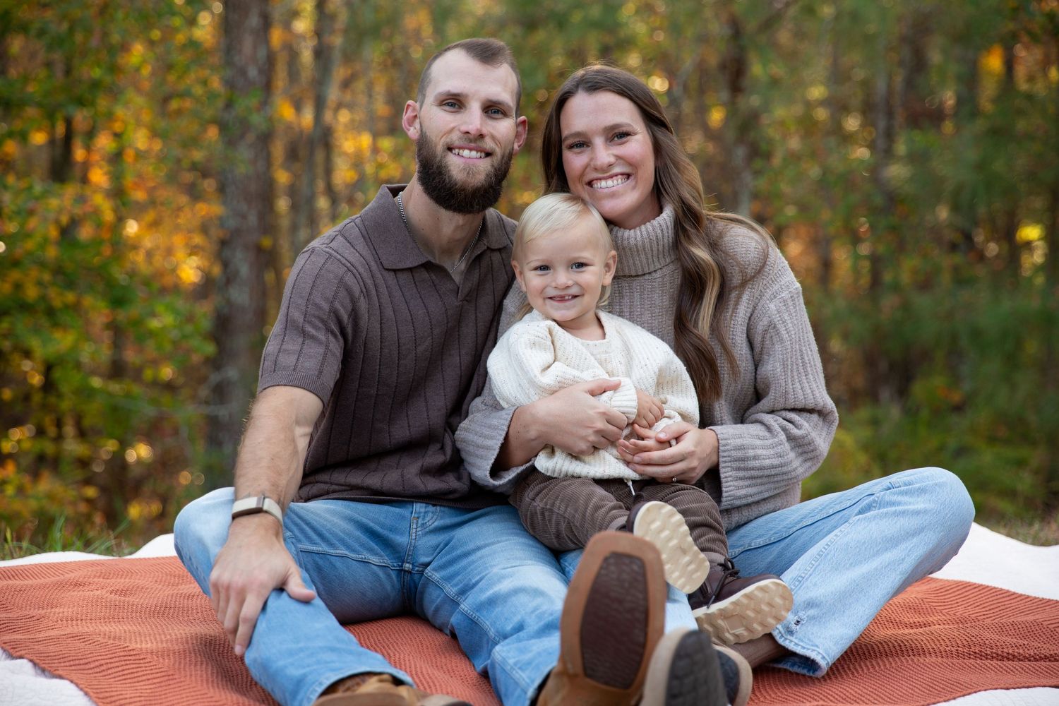A family relaxes together on a orange blanket during an autumn outdoor photoshoot-Northwest Georgia Jessica M Cooper Photography LLC