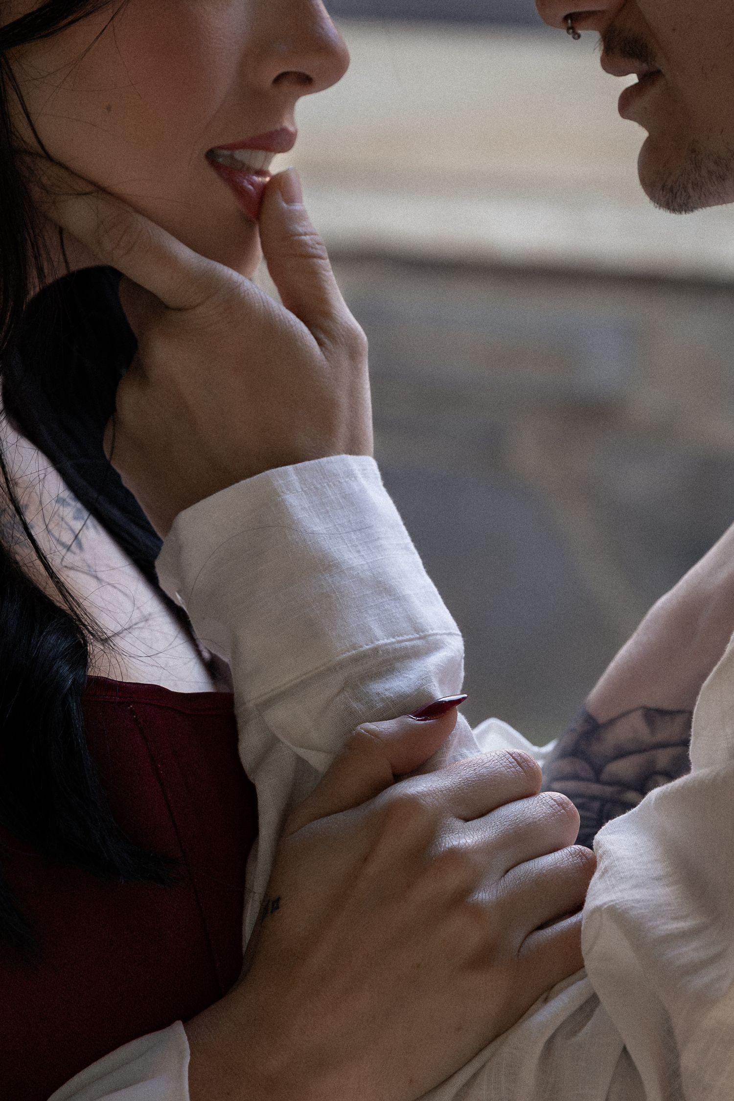 A tattooed man gently touches a woman's lips in an intimate romantic moment, both wearing vintage-style clothing. Berry College Rome, GA