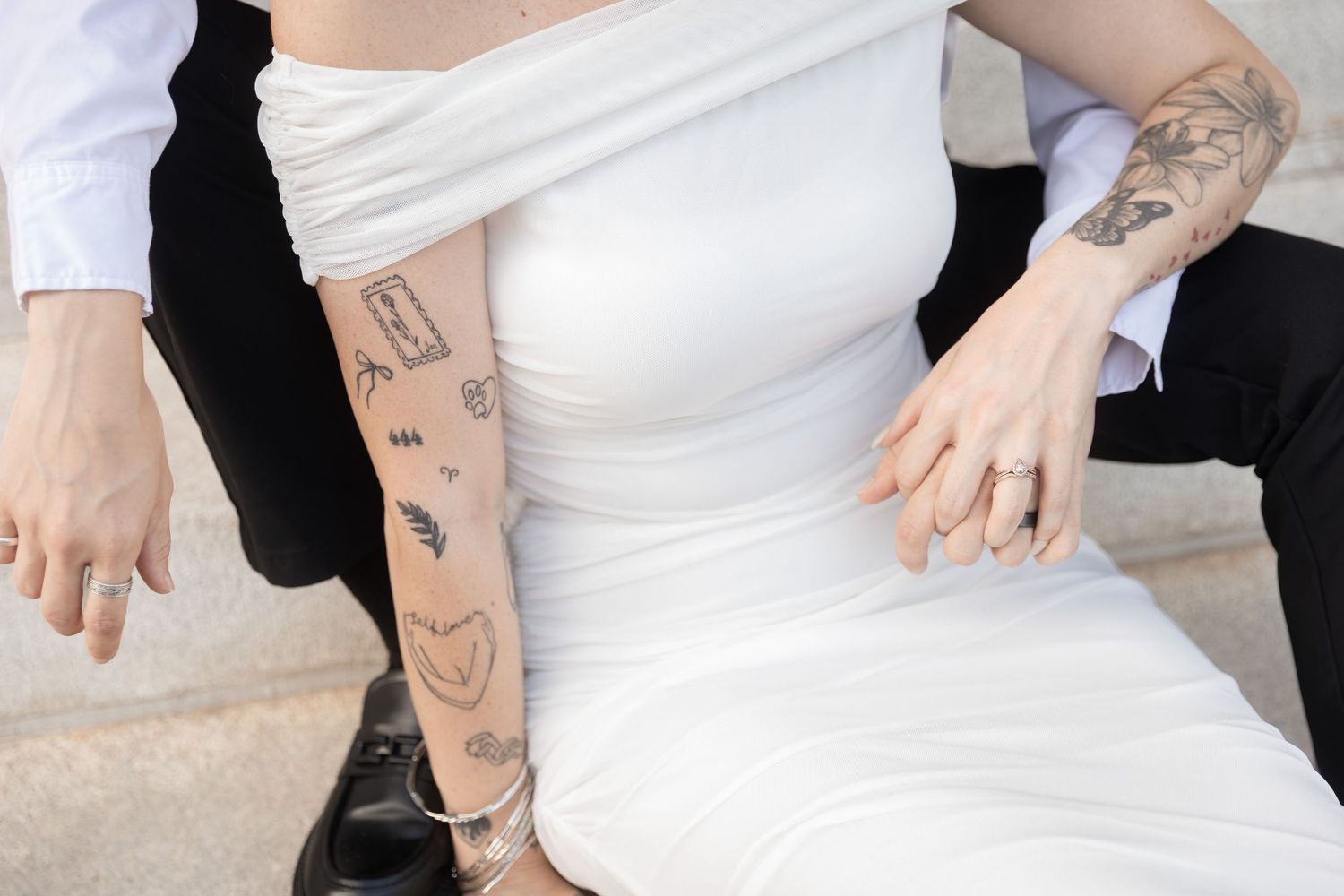 Close-up of a bride in a white dress with tattoos on her arms, sitting beside a groom in a black suit. Downtown Rome, GA