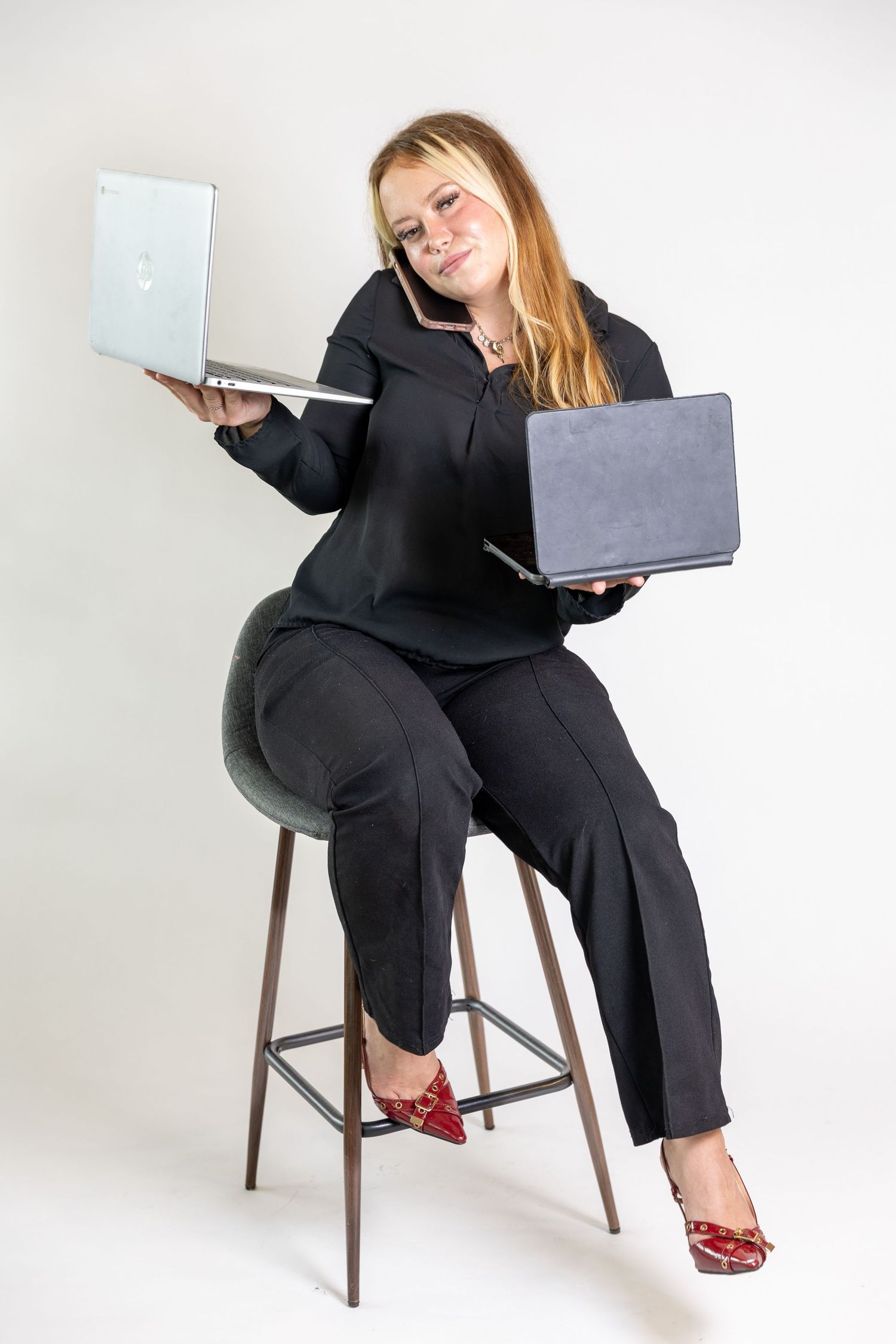 Busy businesswoman in black suit multitasking with two laptops while talking on phone, seated on bar stool Branding session Acworth, GA