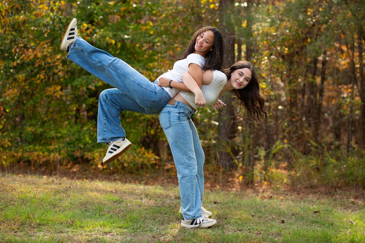 Two people in casual wear jump playfully in an autumn outdoor setting-Jessica M Cooper Photography LLC Rome GA