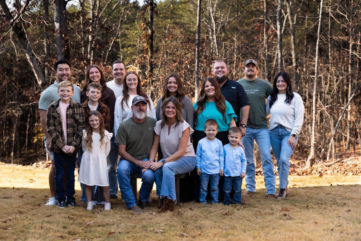 A group of people sitting together outdoors in a casual formation against a wooded backdrop by Jessica M Cooper Photography LLC in NWGA