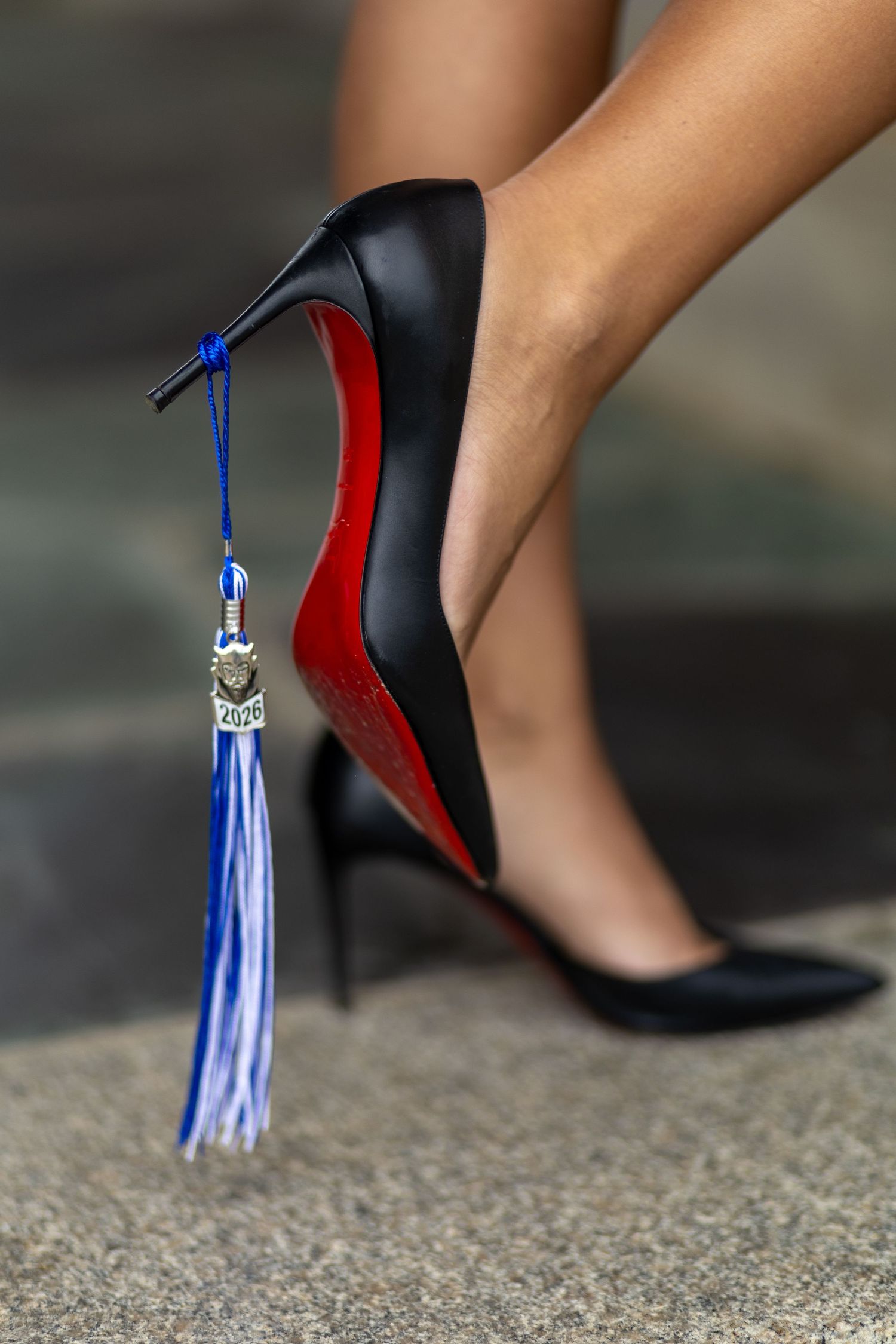 Black stiletto heels with red soles adorned with a blue and white graduation tassel on the heel. Senior Photographer Rome GA