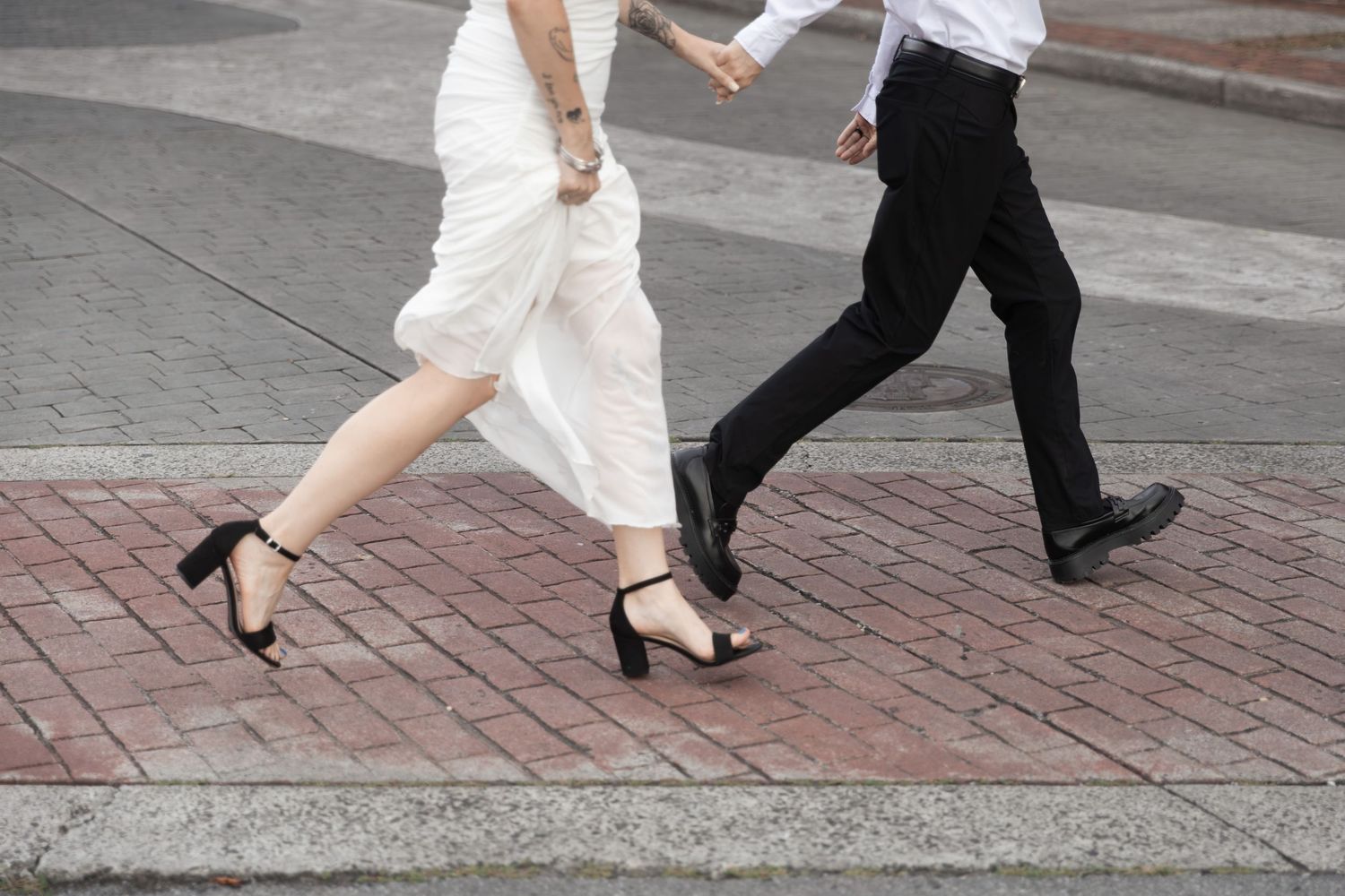 Bride in white dress and groom in black suit walking hand in hand across a brick sidewalk.  Downtown Rome, GA Jessica M Cooper Photography
