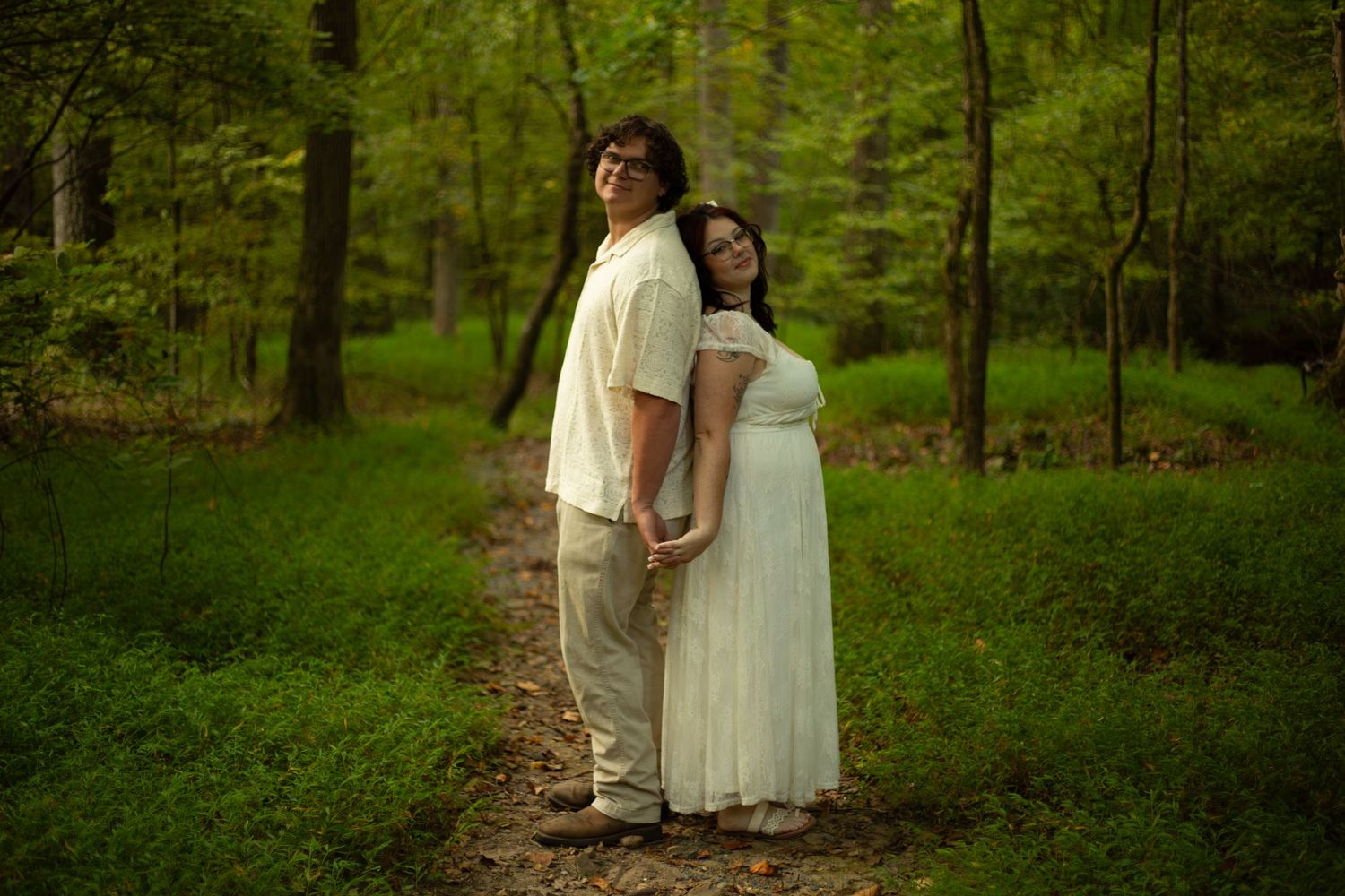 Couple standing together in lush green forest wearing casual clothing-Jessica M Cooper Photography LLC Rome GA