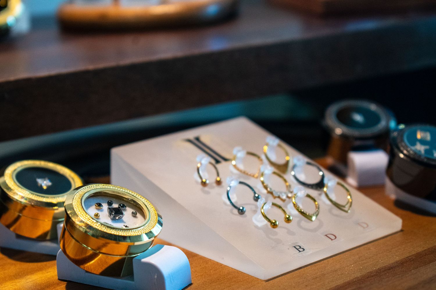 Luxury watch components and gold rings displayed on a wooden surface in an upscale jewelry store.