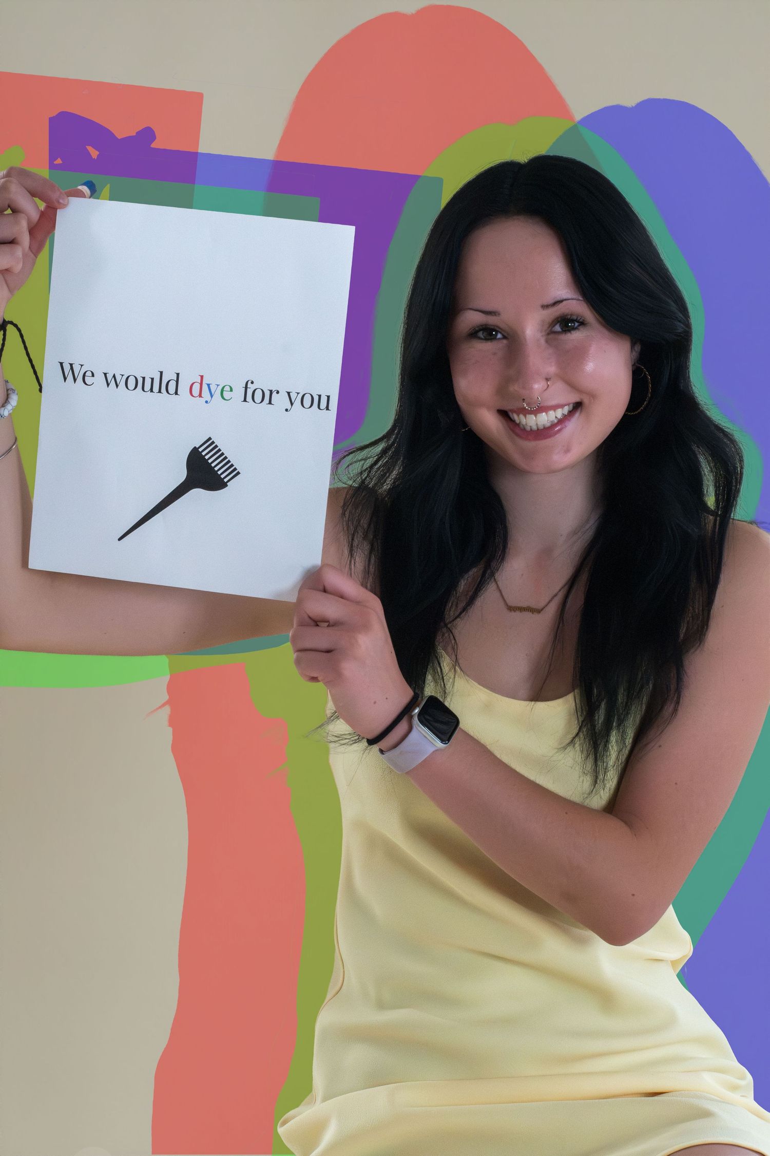 Smiling woman in yellow dress holds a sign reading We would dye for you with a hair dye brush graphic.