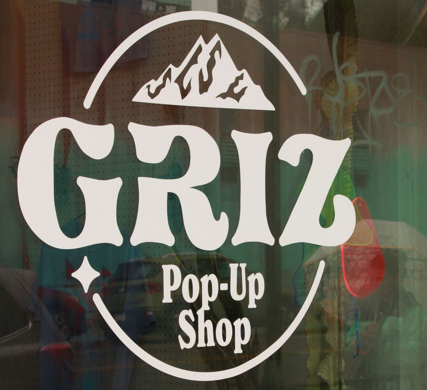 Griz Pop-Up Shop logo on a storefront window featuring mountain peaks and bold retro typography.
