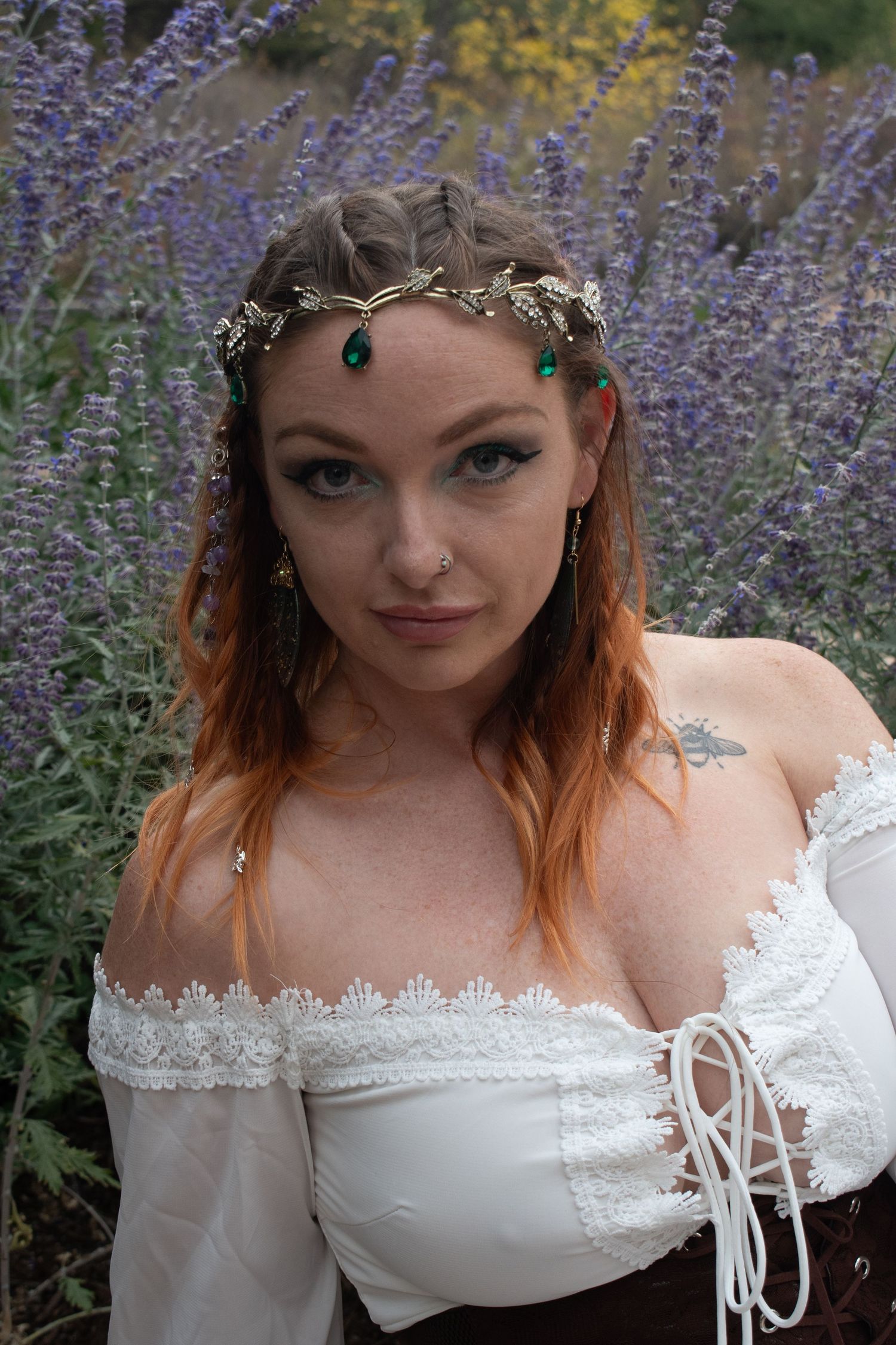 Red-haired woman in white renaissance dress with green jeweled crown in lavender field.