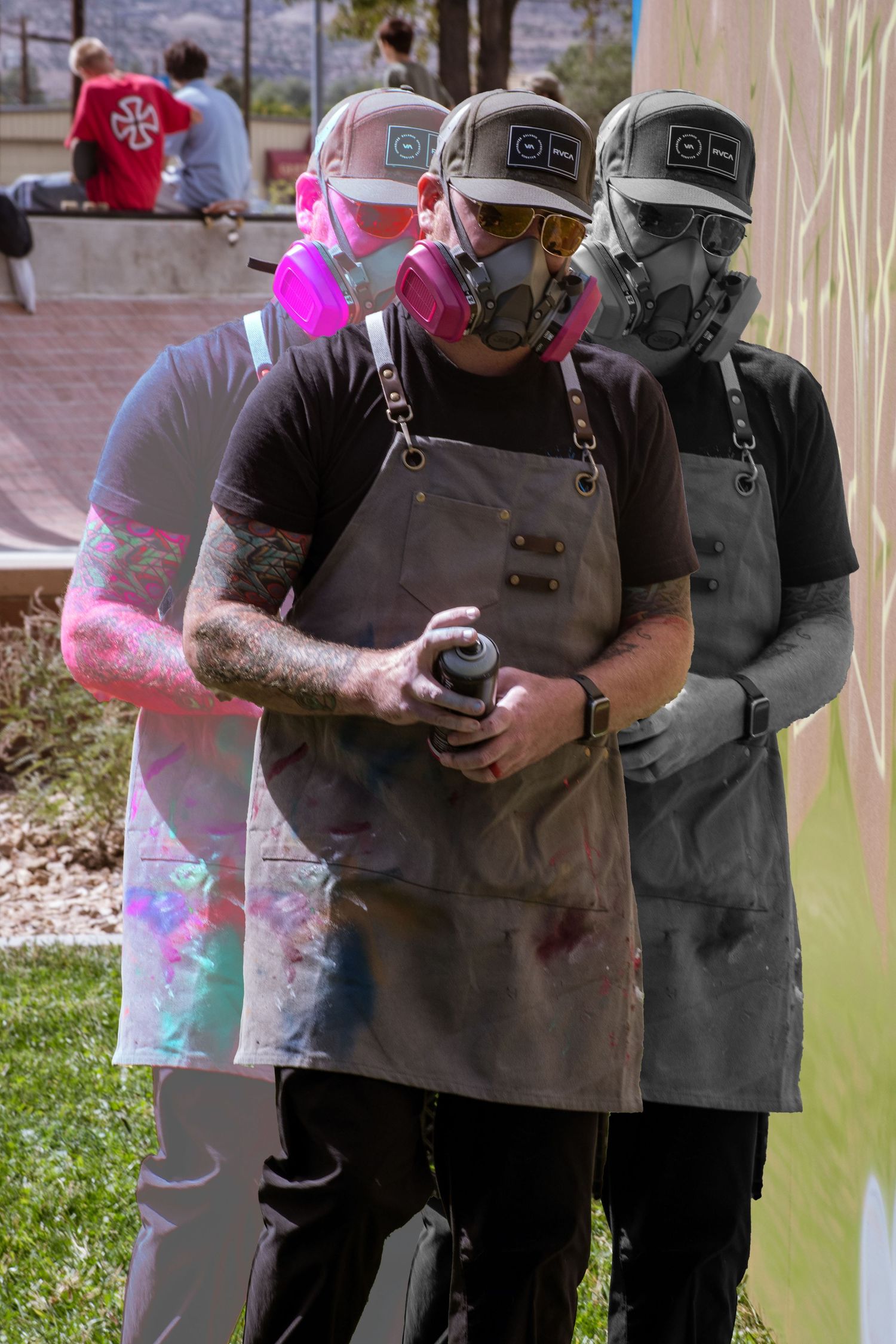 Three graffiti artists wearing respirator masks and aprons hold spray cans while creating street art outdoors.