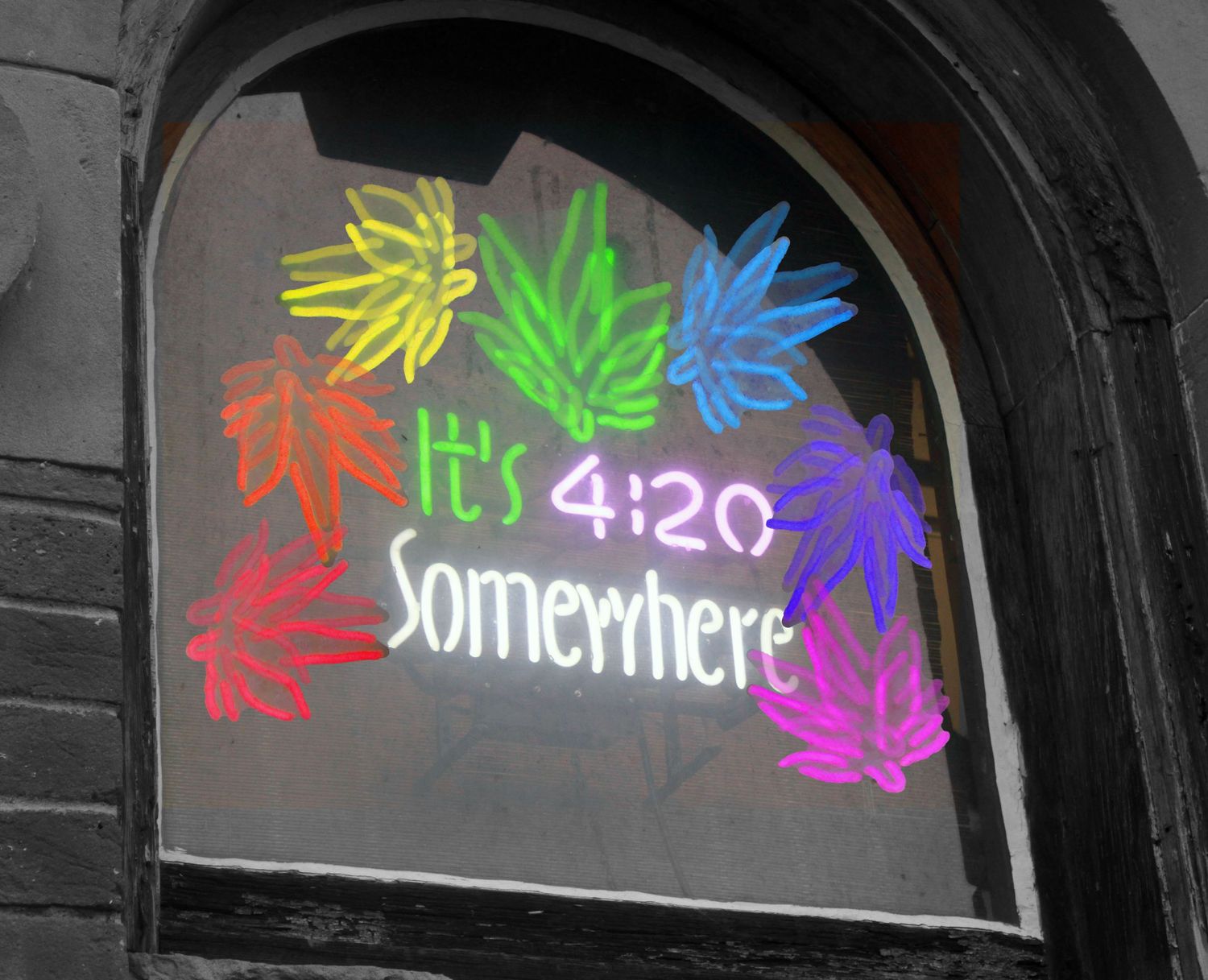 Colorful neon marijuana leaf drawings on a window with 