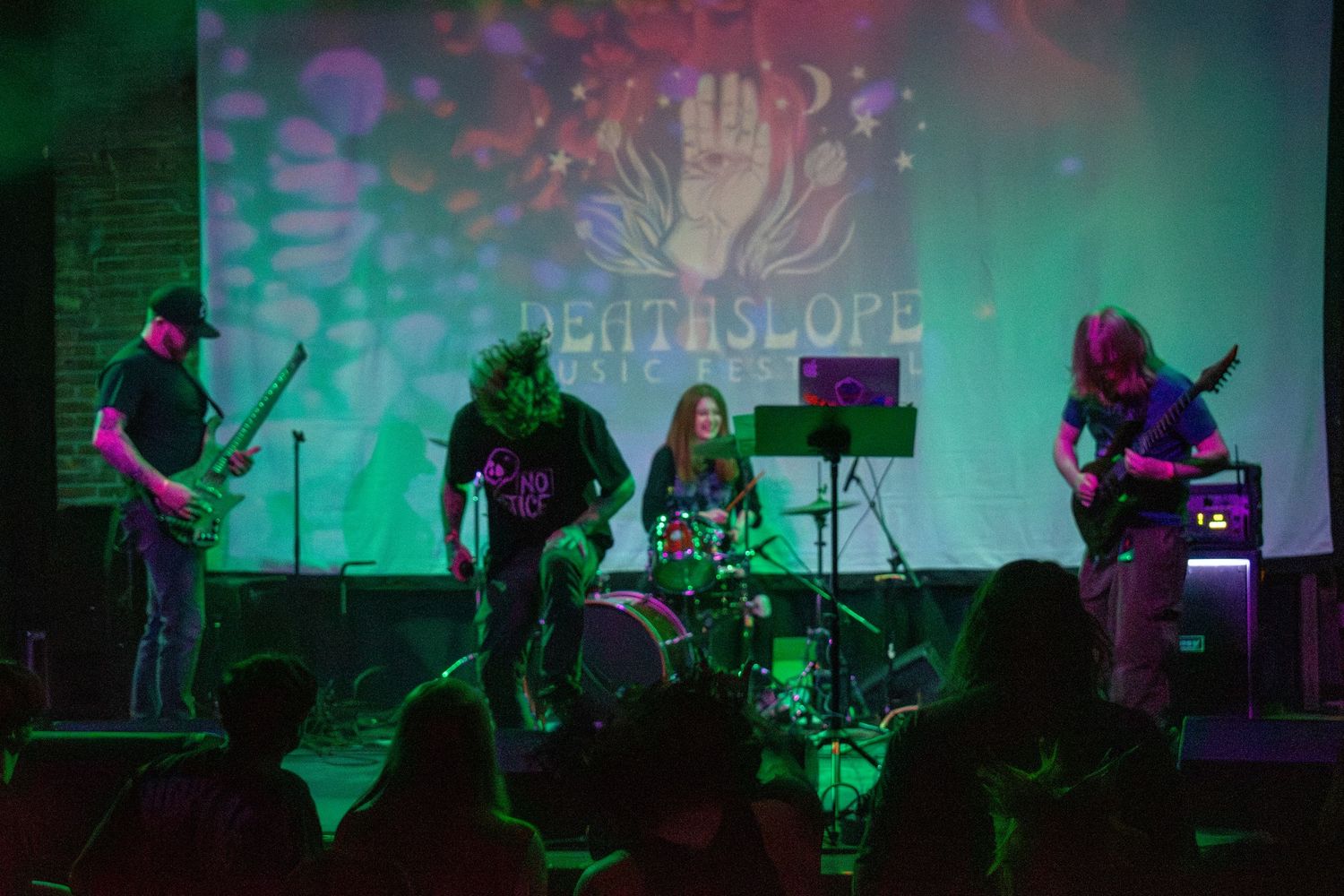 Deathslope band performing live on stage with colorful green and pink lighting in a small music venue.