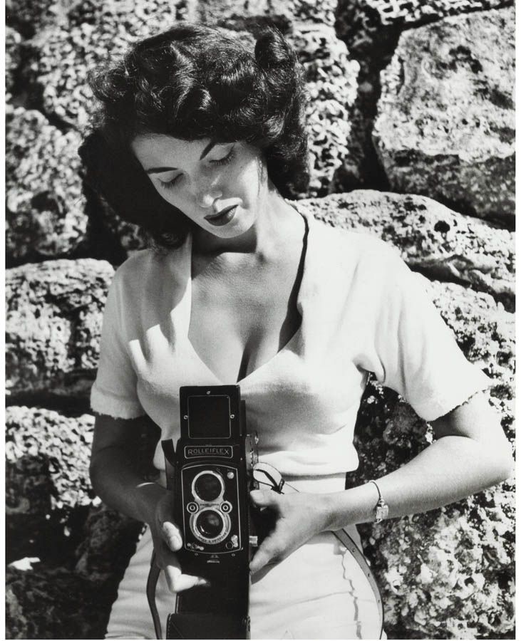 woman holding Rolleiflex twin-lens camera outdoors. Vintage black and white photo of Bunny Yeager for quote