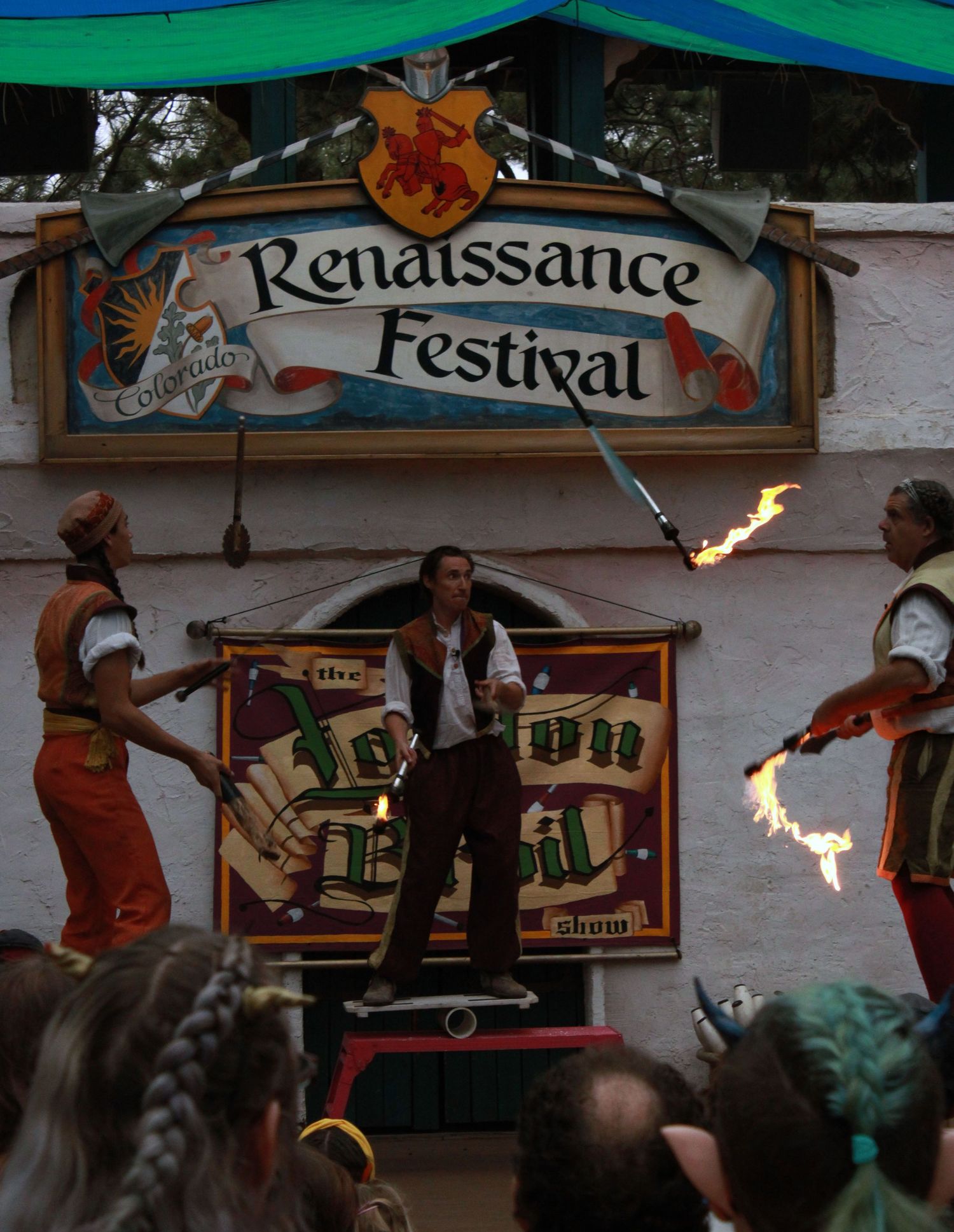 Fire juggler performs at Colorado Renaissance Festival stage before a crowd of spectators.