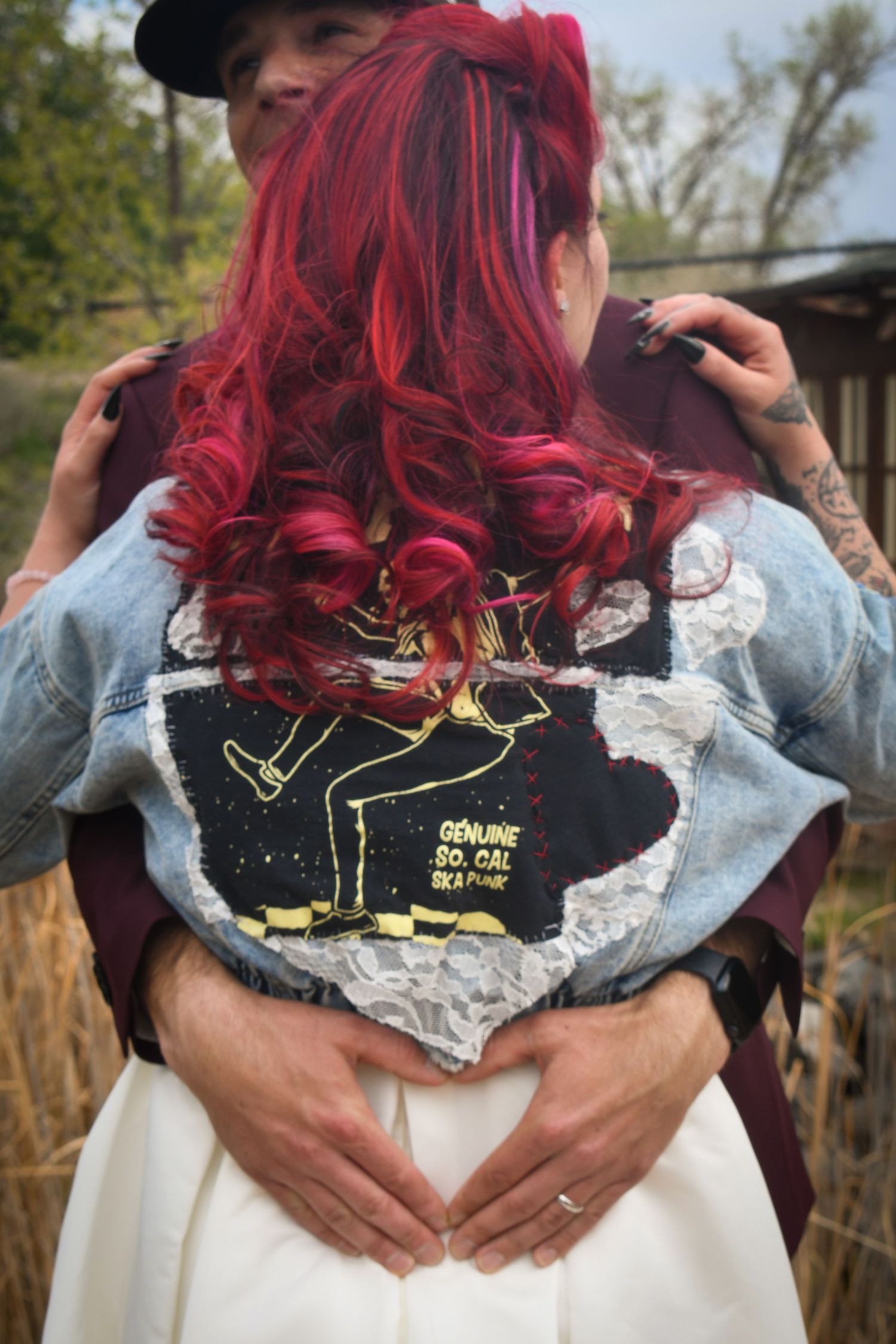 Couple embracing, woman with vibrant red curly hair wearing a denim jacket with Genuine So. Cal Ska patch.