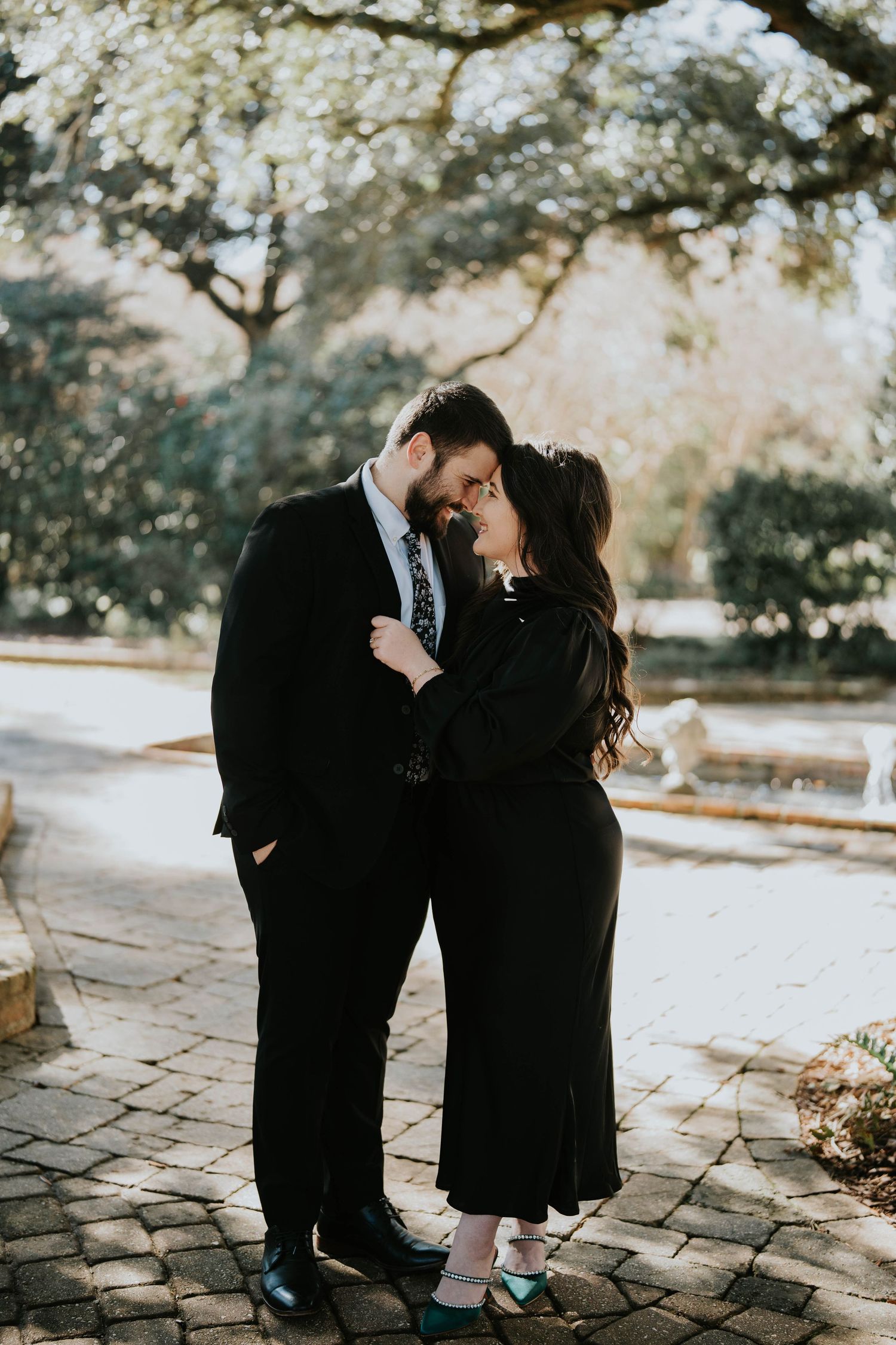 Couple in black outfits sharing intimate moment on stone pathway during autumn photoshoot.