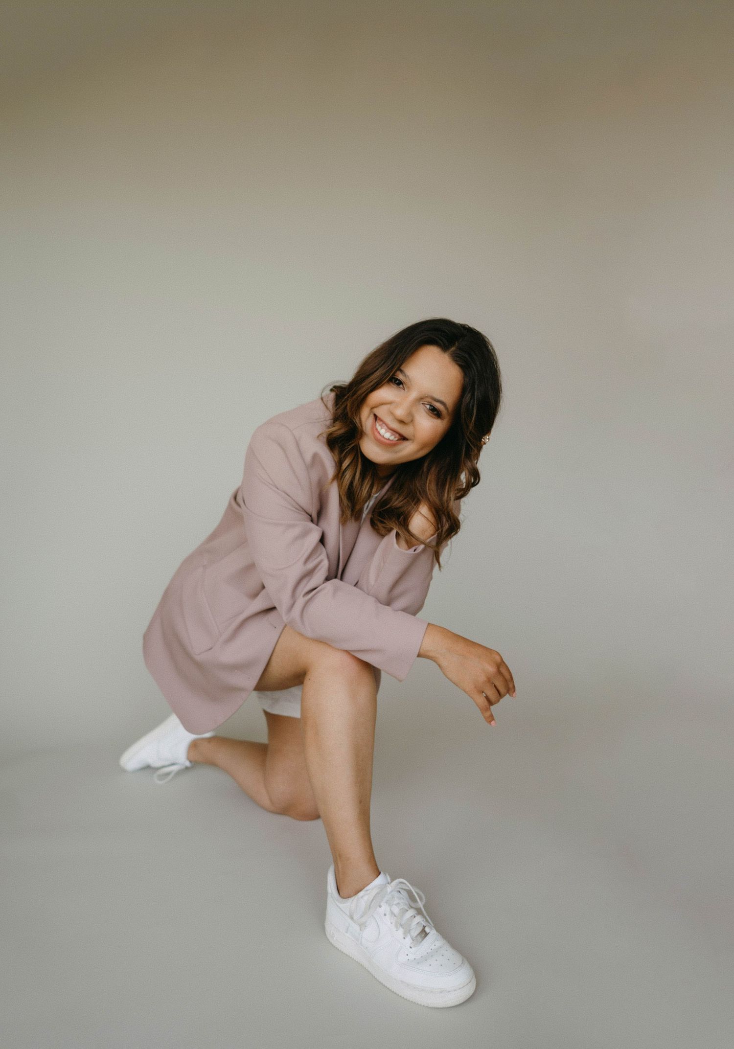 Fashion portrait in soft pink outfit against neutral studio background.
