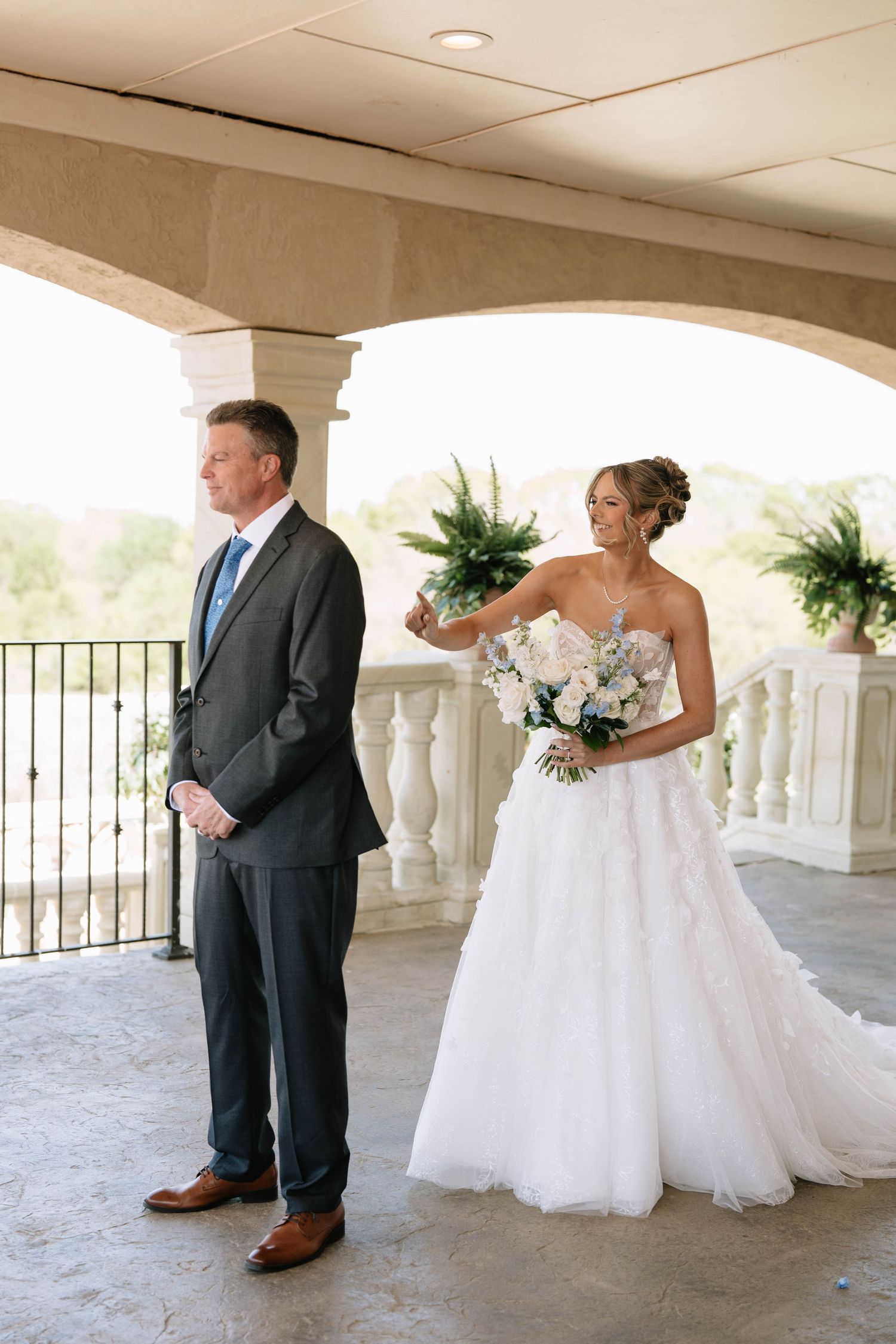 Wedding party members pose for first look photos on an elegant covered balcony.