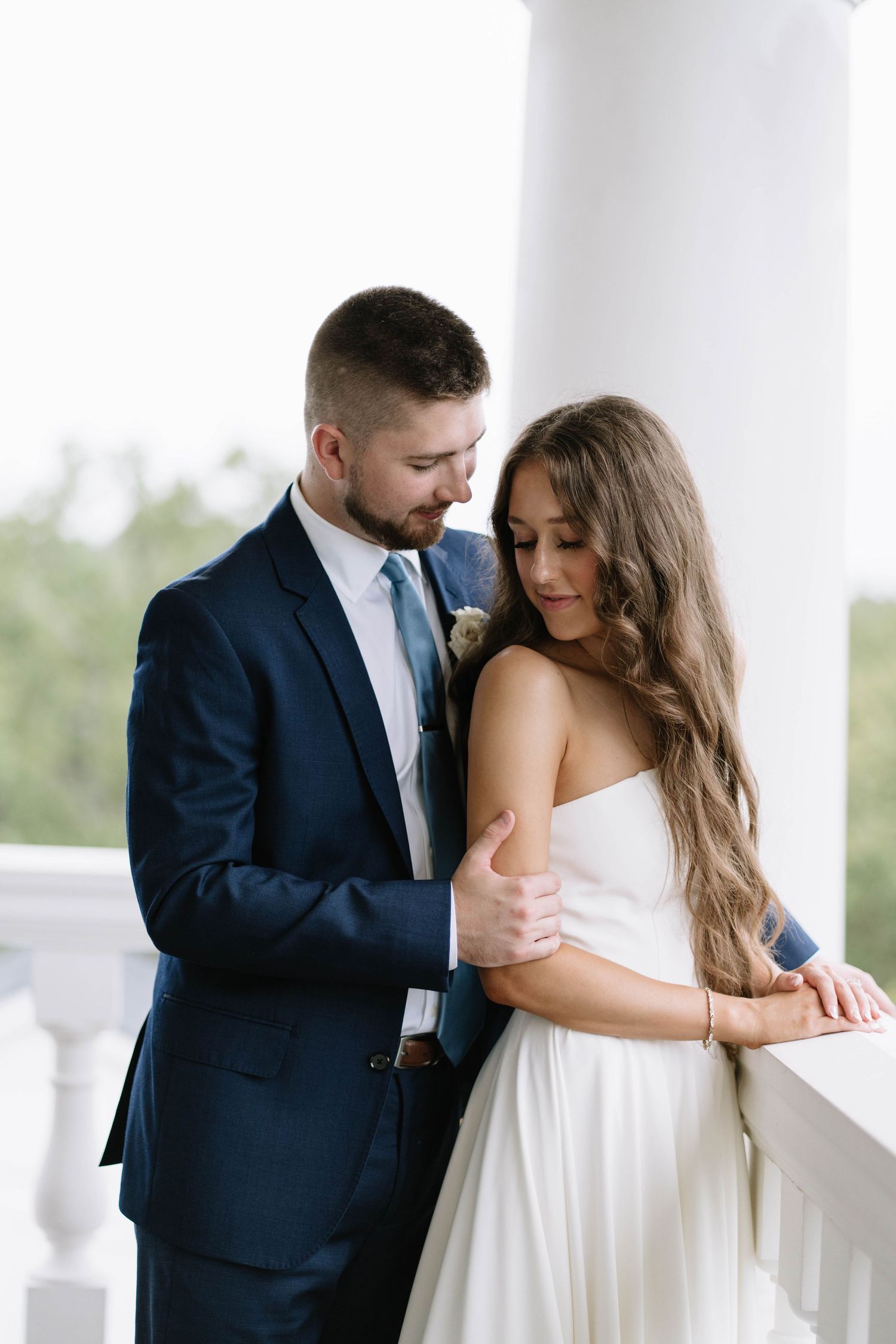 A romantic moment between newlyweds on a white columned porch. Dallas, Texas.