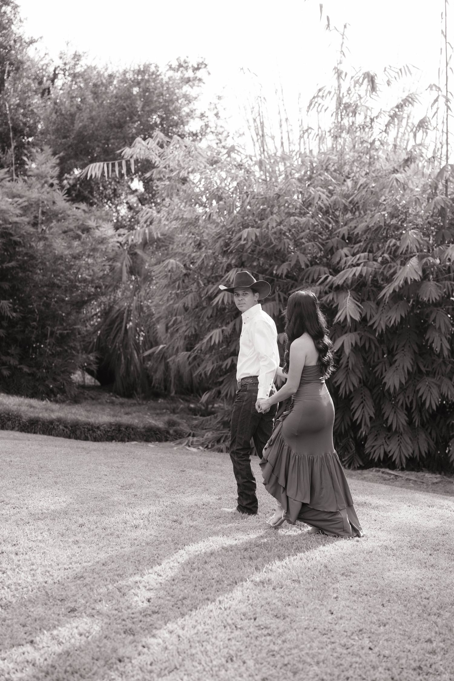 A couple walking through a lush garden path in black and white photography.