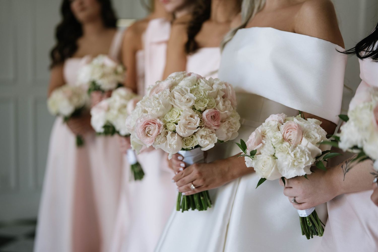Delicate pink and white wedding bouquets held against light colored dresses.
