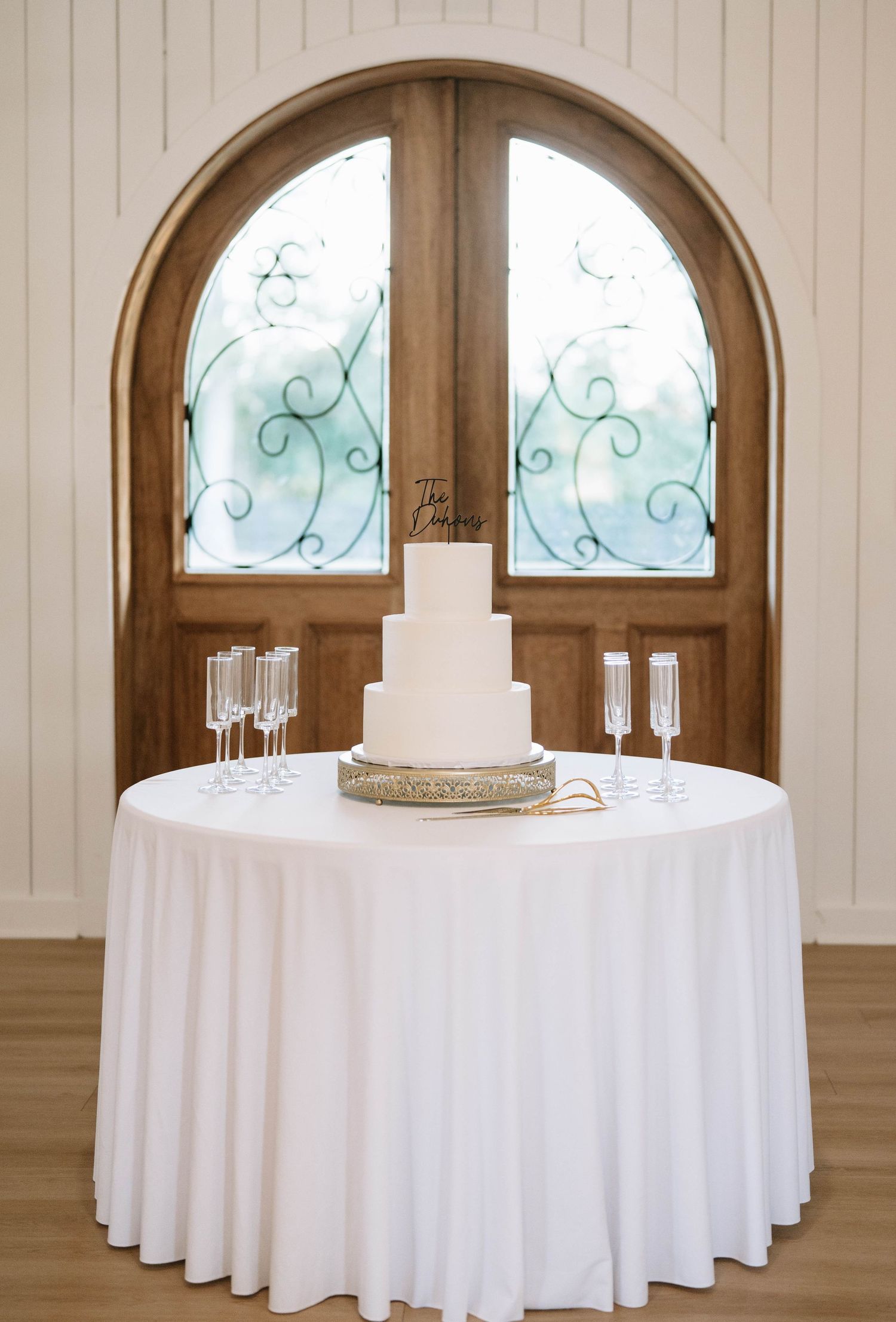 Elegant wedding reception setup with round tables and arched windows.